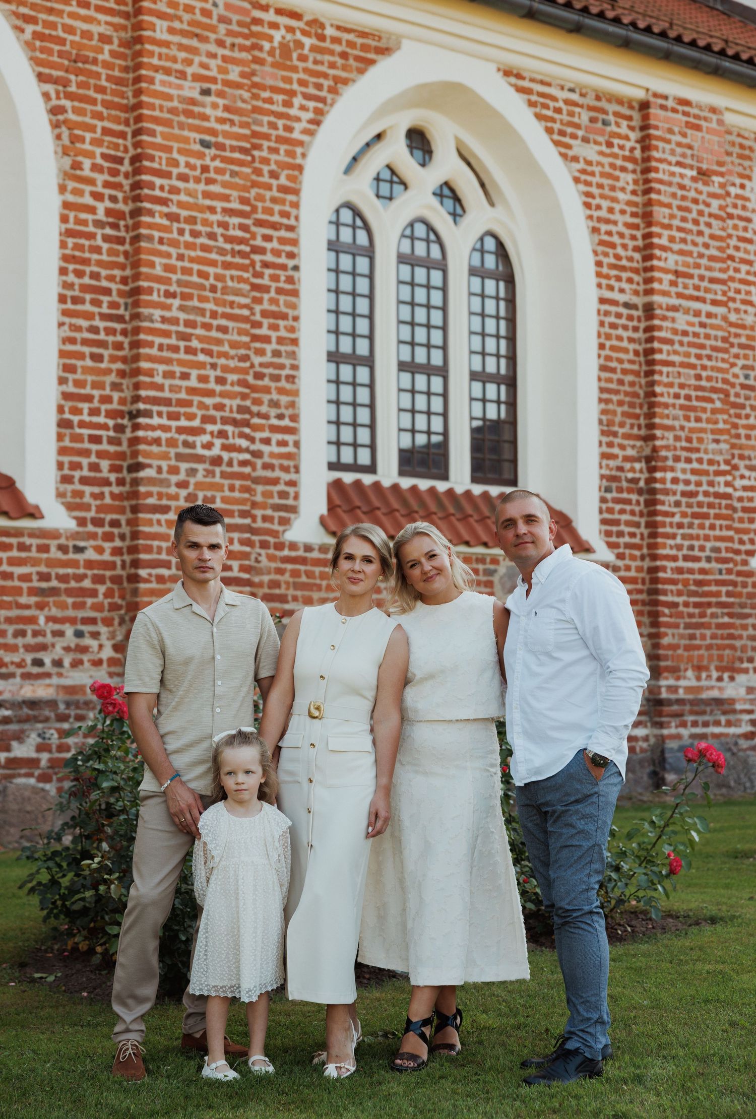Group photo session against the backdrop of a historic red brick church with Gothic windows.