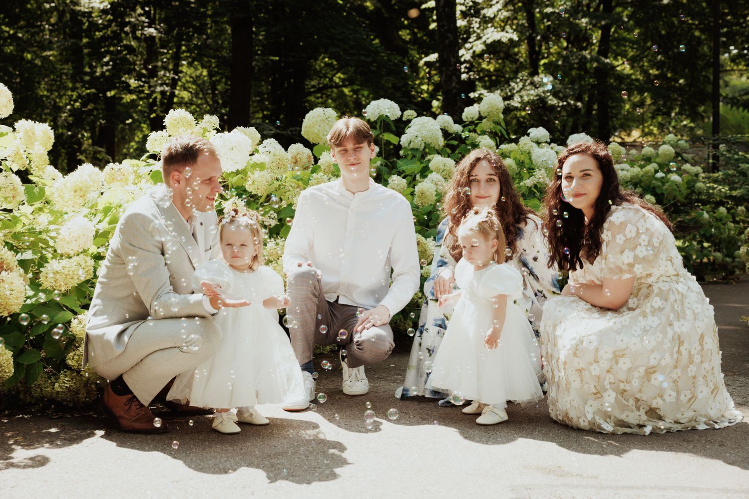 A series of outdoor wedding party photos with people in white dresses and suits sitting together on stone steps.