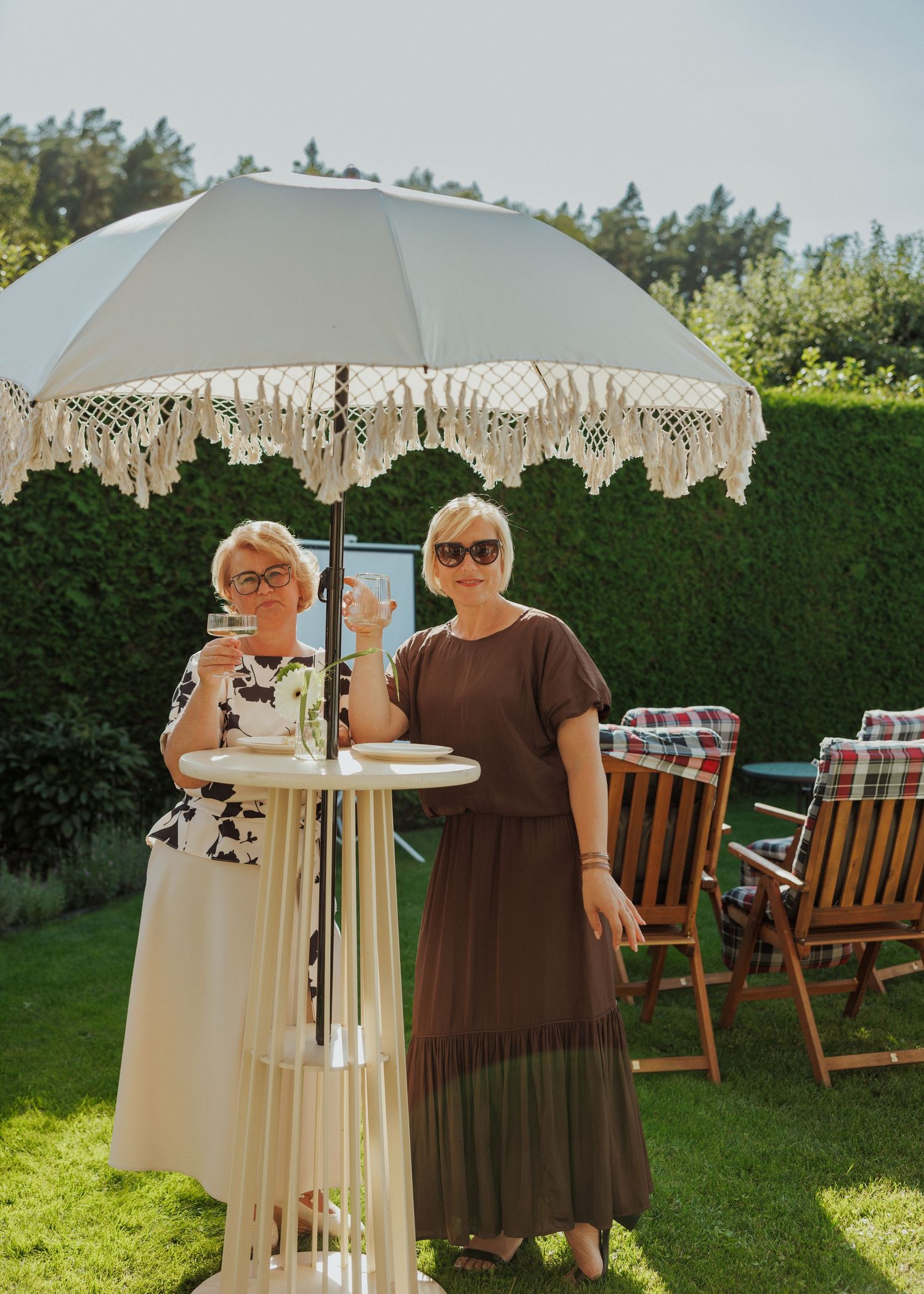 Outdoor garden setting with decorative white umbrellas and wooden chairs on grass.