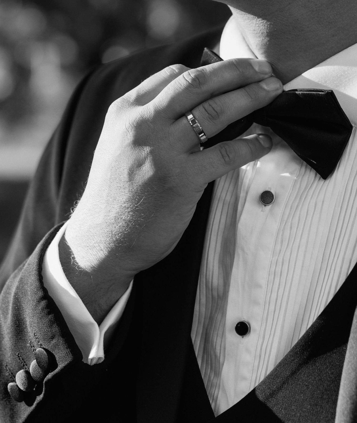Black and white detail shot of formal wedding attire and hands.