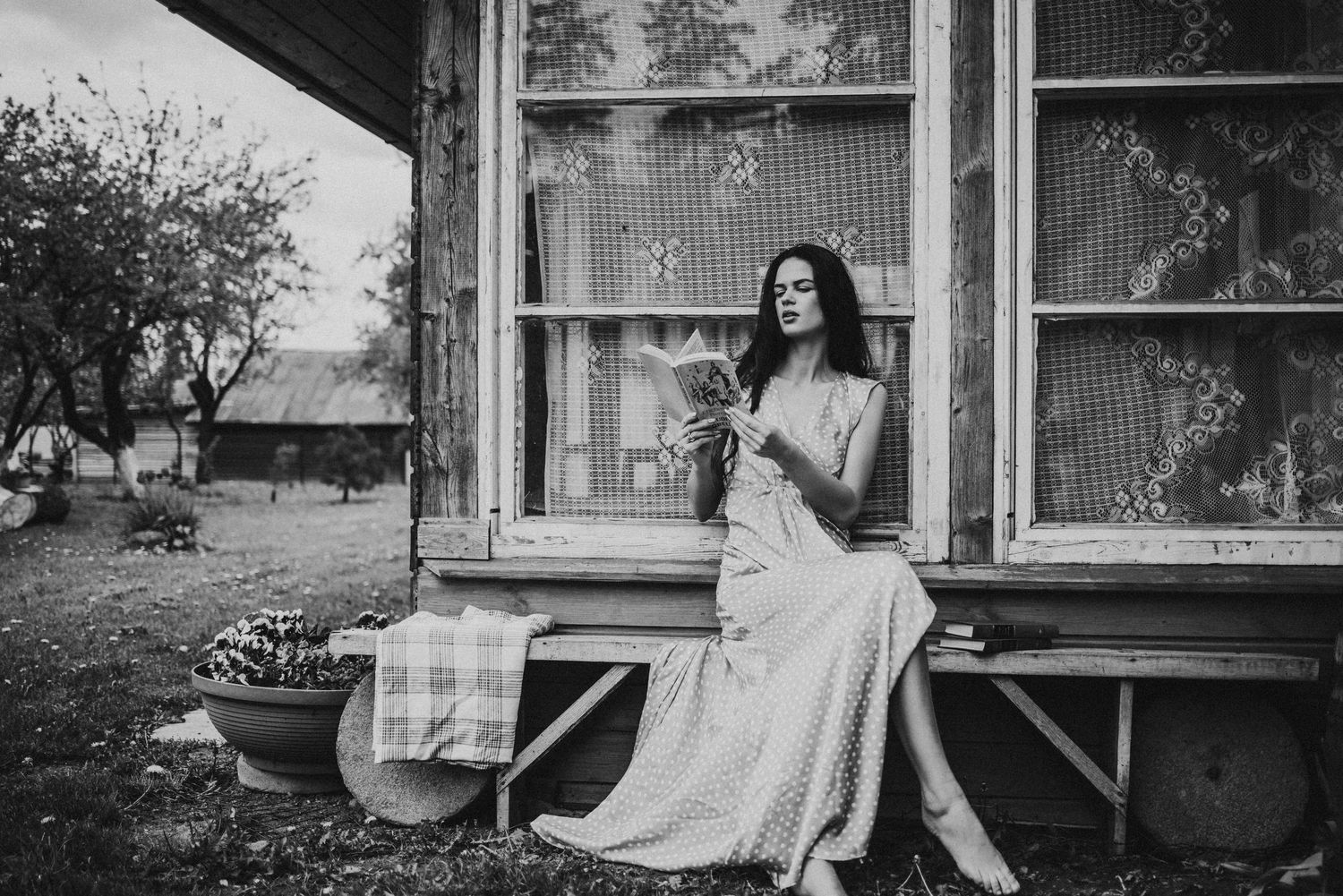 Black and white photograph capturing contemplative moment on a rustic porch.
