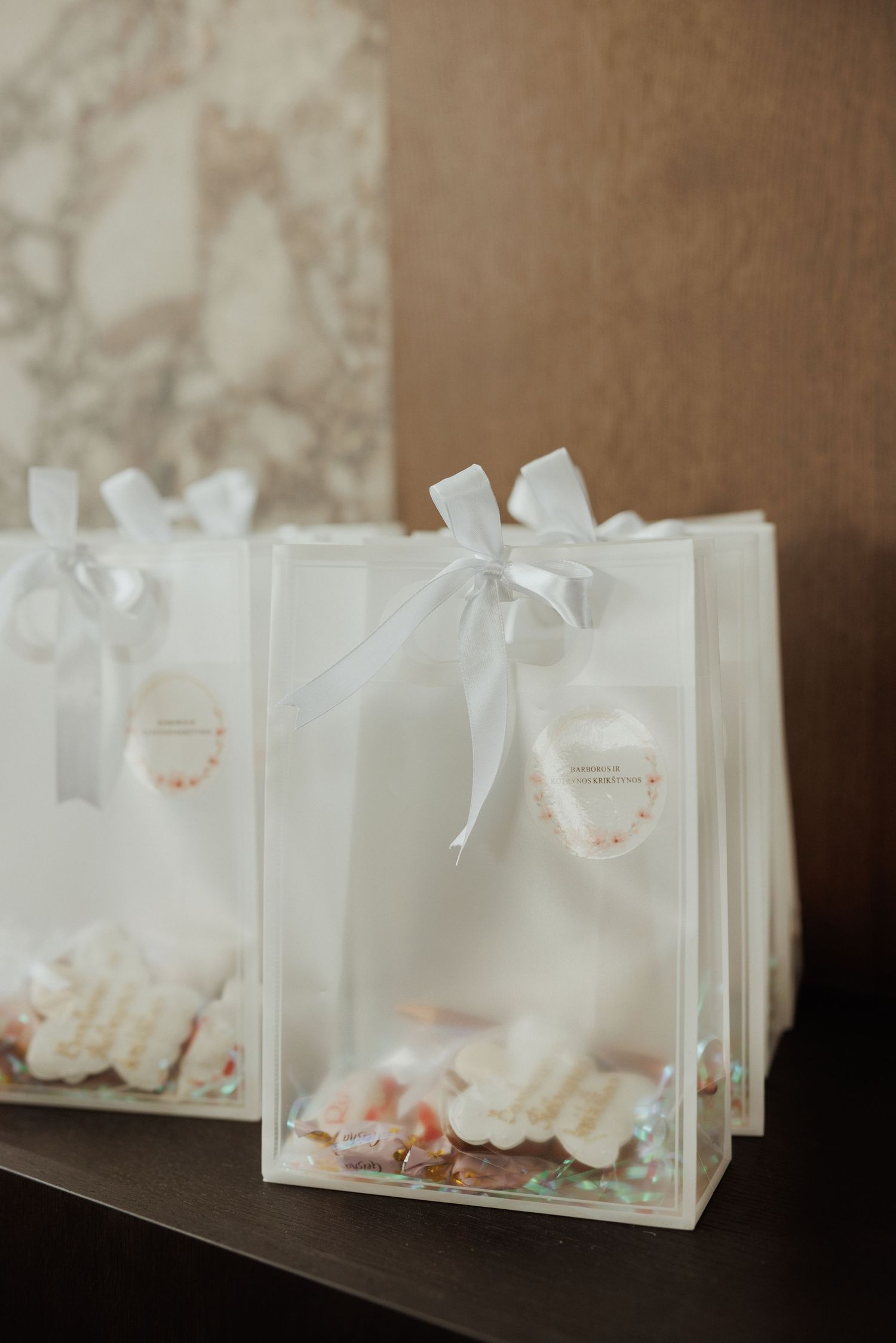 Row of white gift bags with ribbons arranged for party favors.