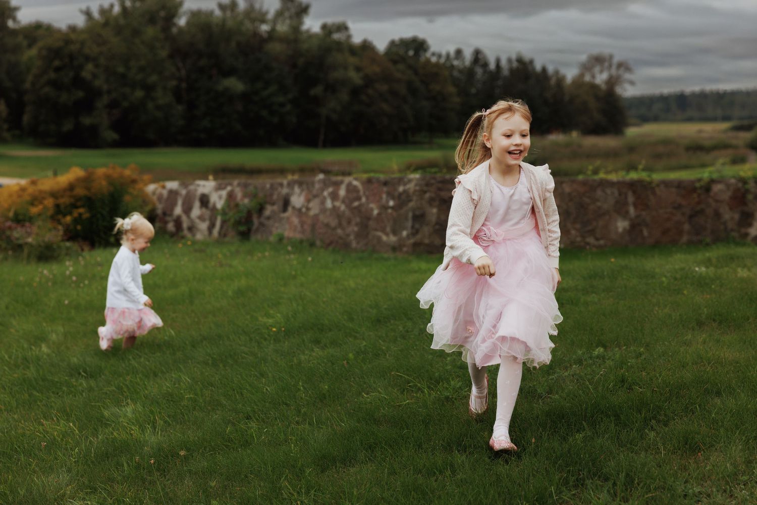 A series of outdoor family portraits showing sweet interactions in a grassy field with cloudy skies.