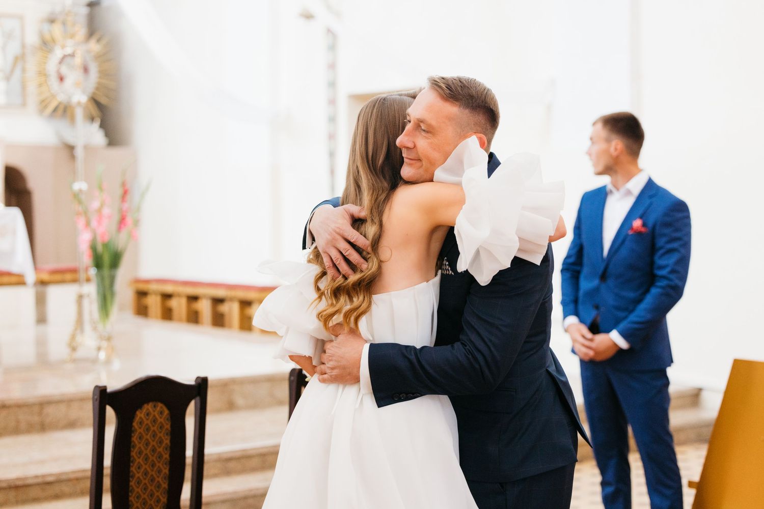 Wedding couple sharing an intimate dance moment in an elegant indoor venue with guests in background.