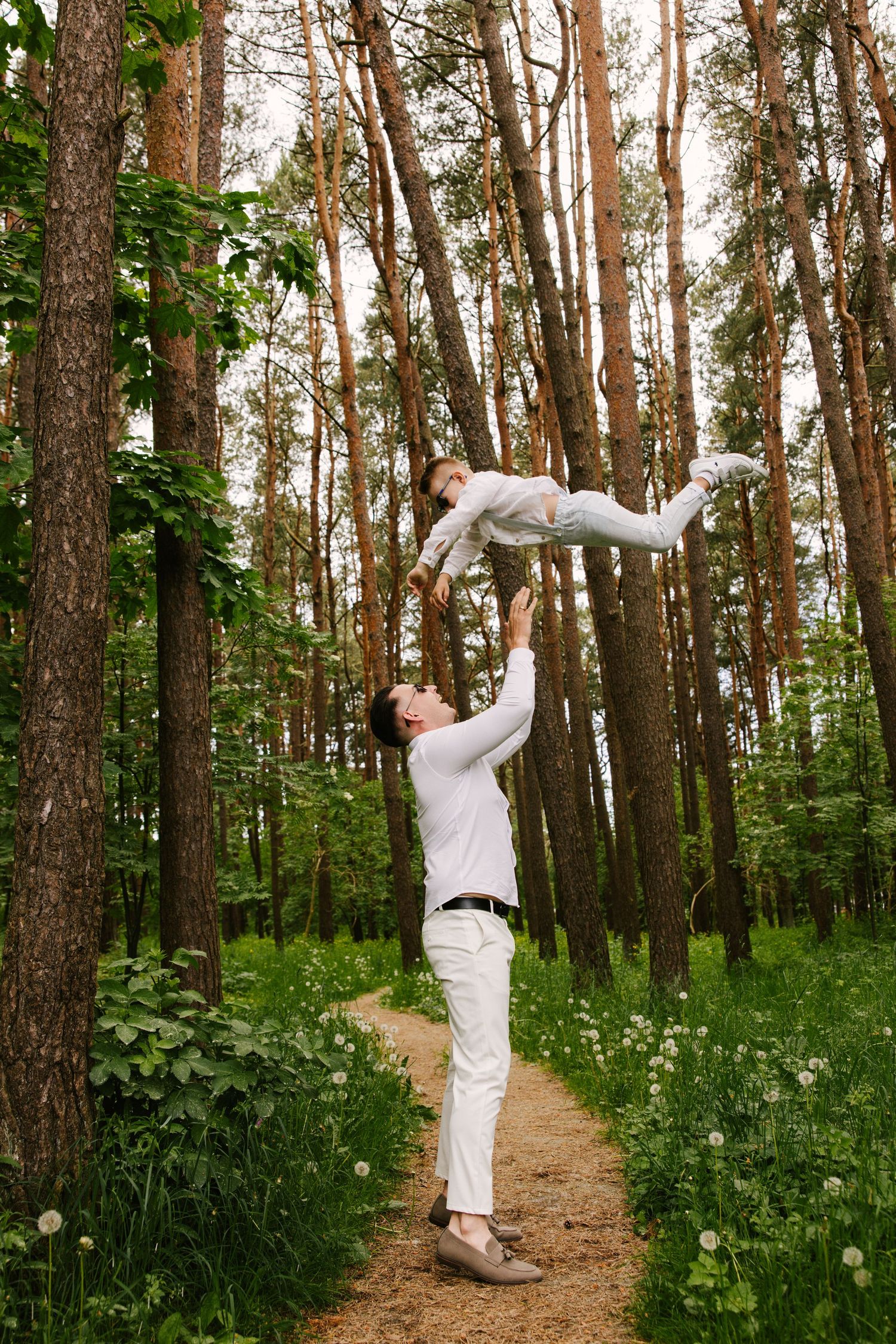 A playful moment captured in a sunlit forest path with tall pine trees.