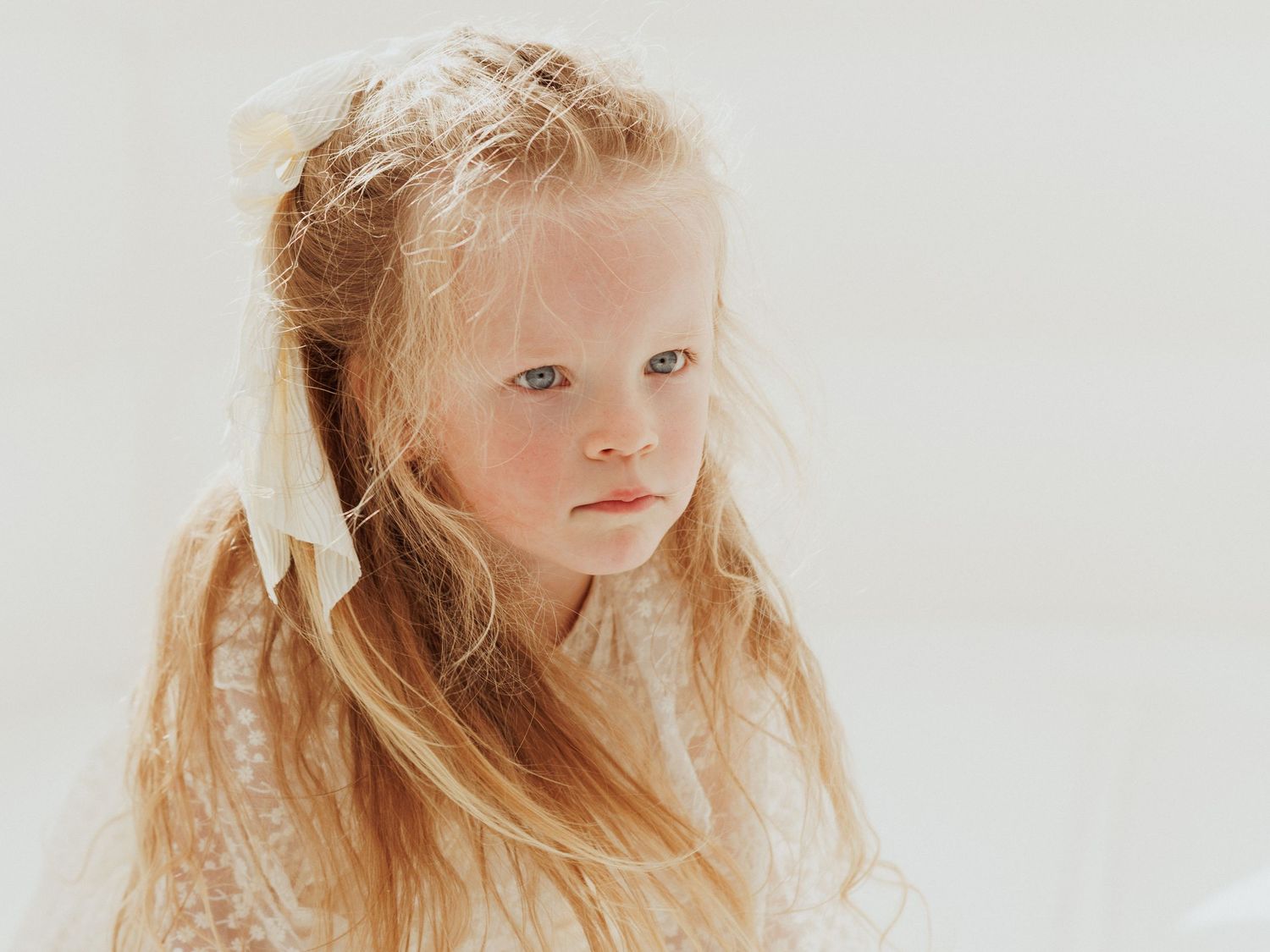 A series of four photos showing a young child with blonde hair against a light background.