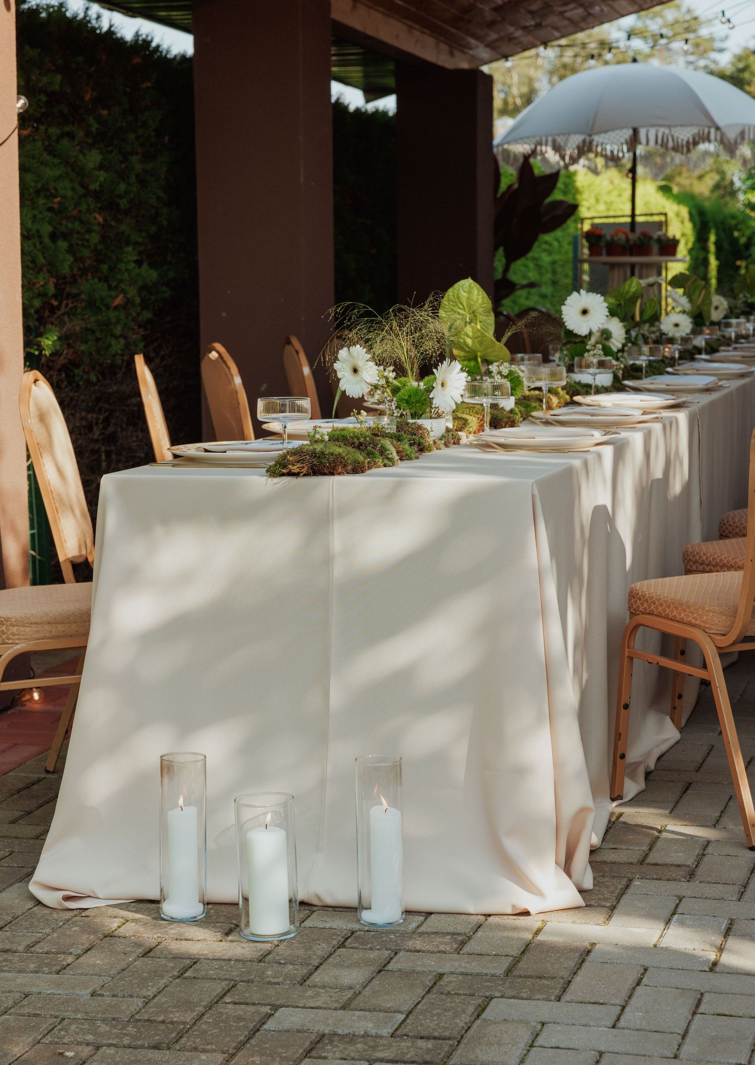 Elegant outdoor wedding reception setup with white tablecloths and wooden chairs.