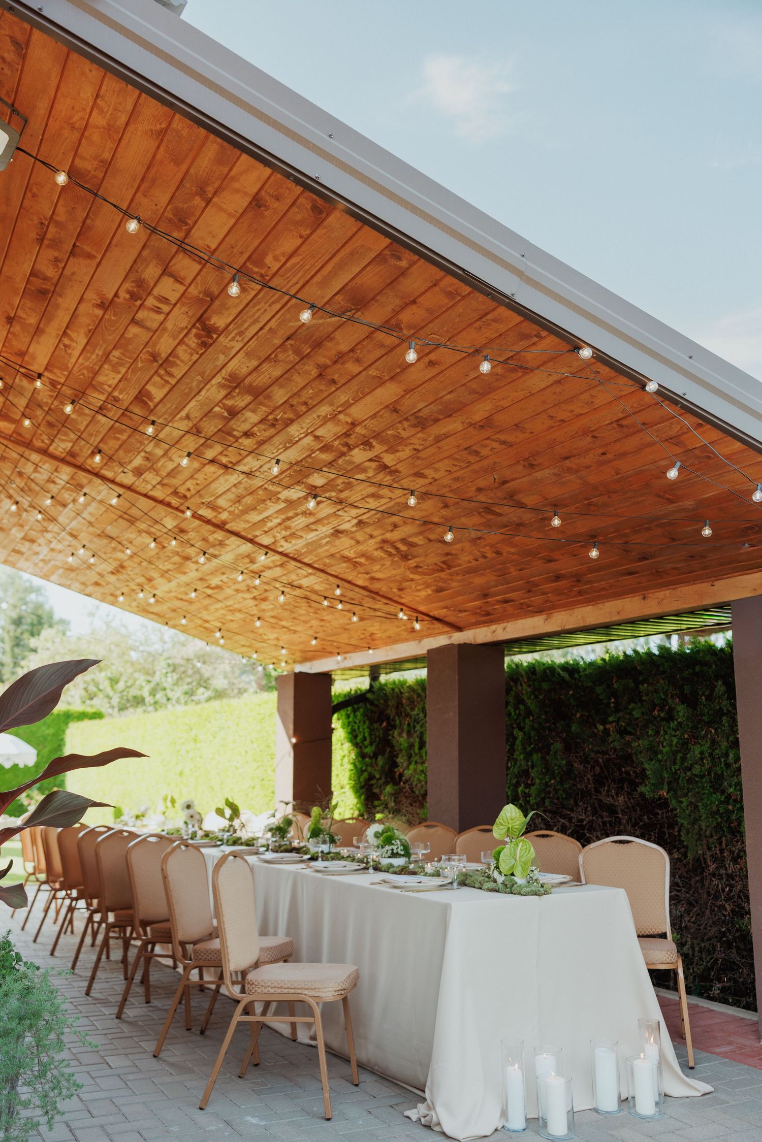 Modern outdoor dining space with wooden ceiling and string lights.
