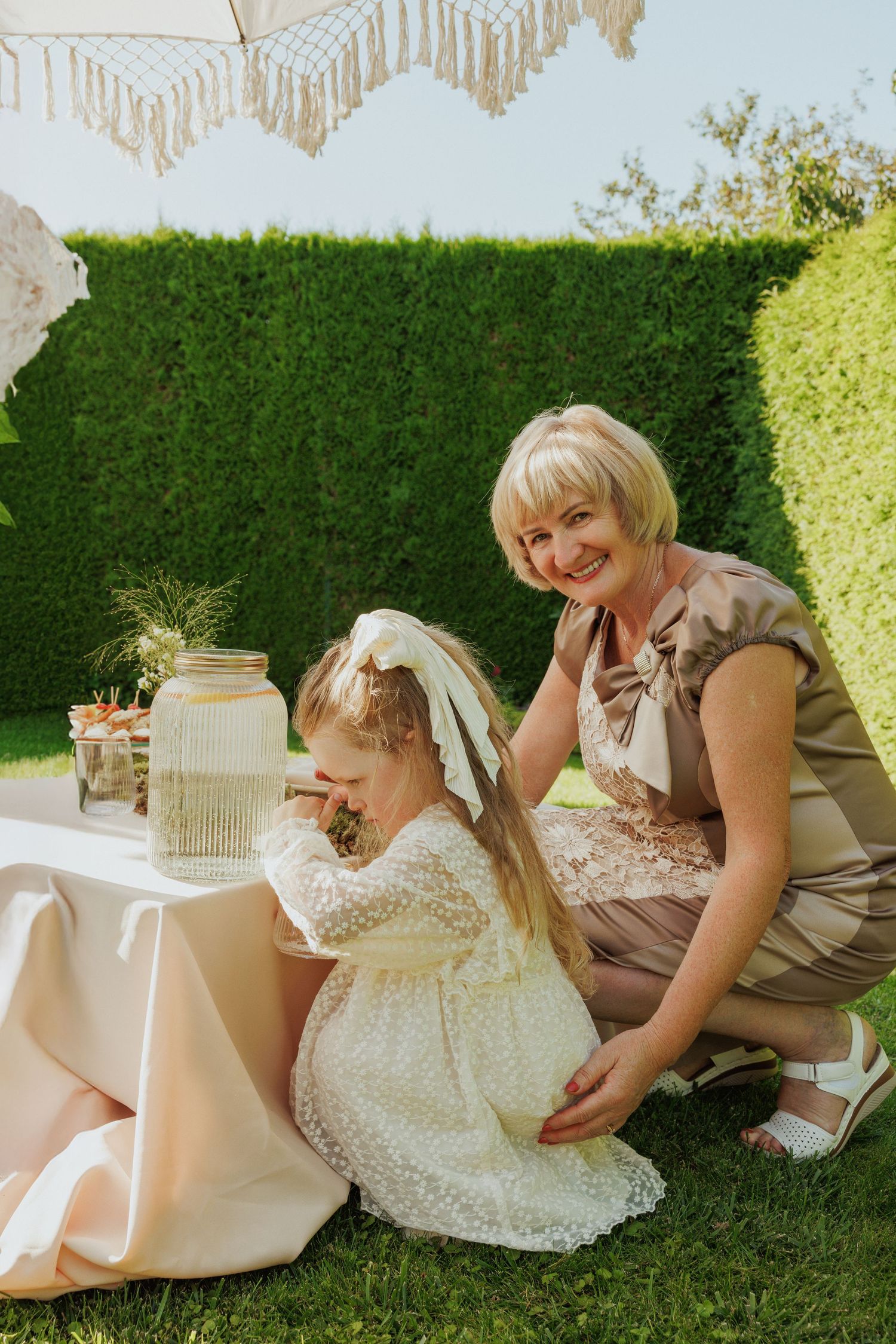 A series of candid outdoor photos showing people in formal attire sitting on grass near a decorative birdcage.