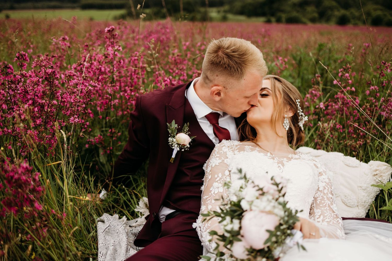 Couple embraces in a field of pink wildflowers during romantic wedding photo session.