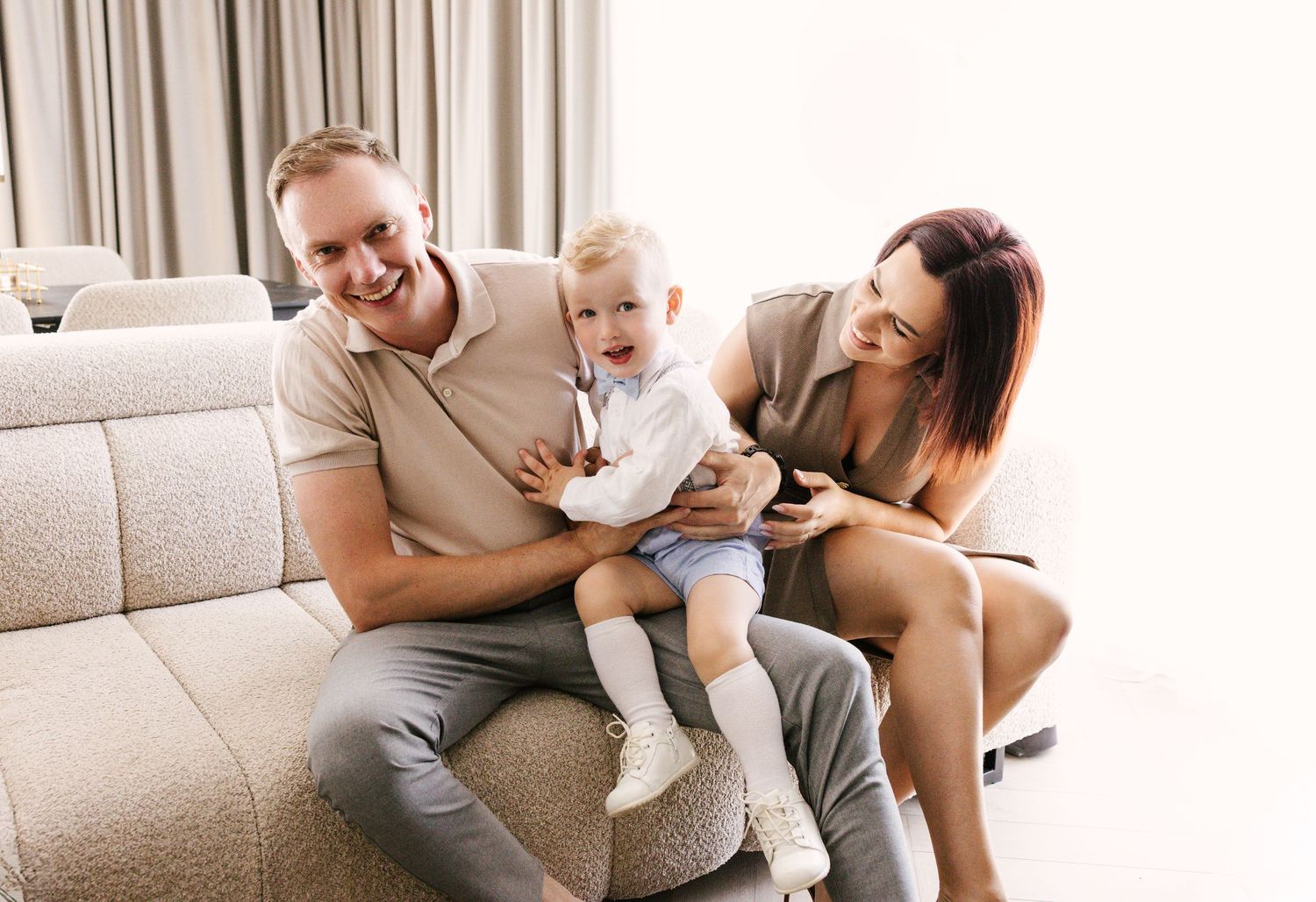 Happy family shares joyful moments together on a cozy grey couch.