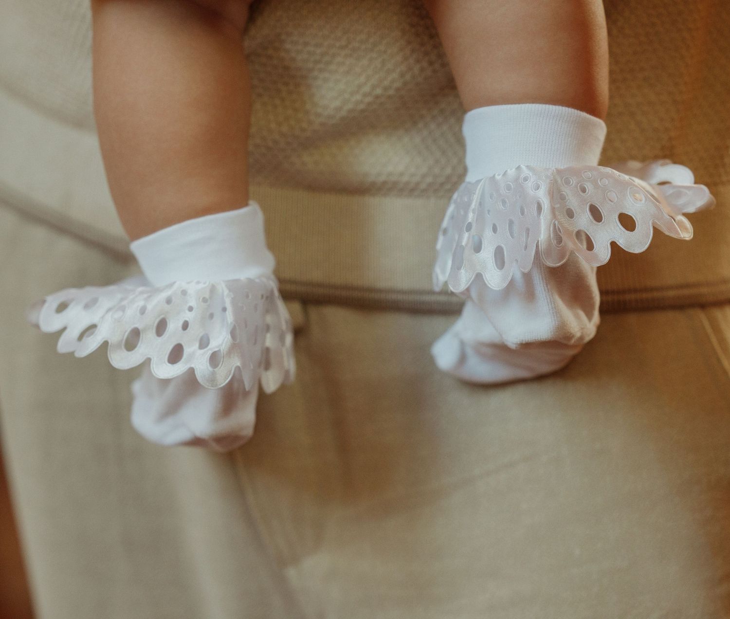 Close-up detail of white lace trim on delicate fabric with soft lighting.