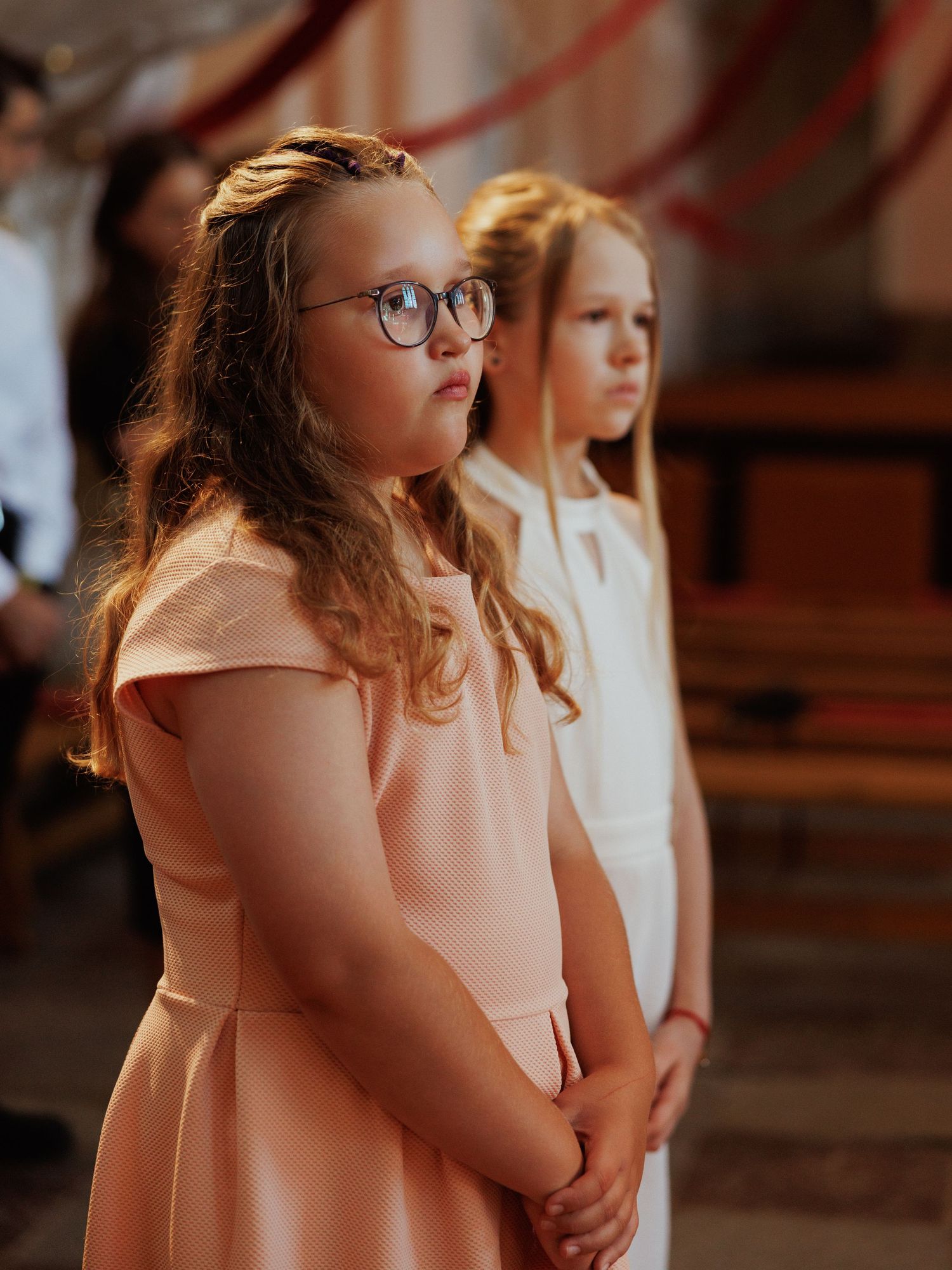 People in white dresses stand in a line during a formal church service.