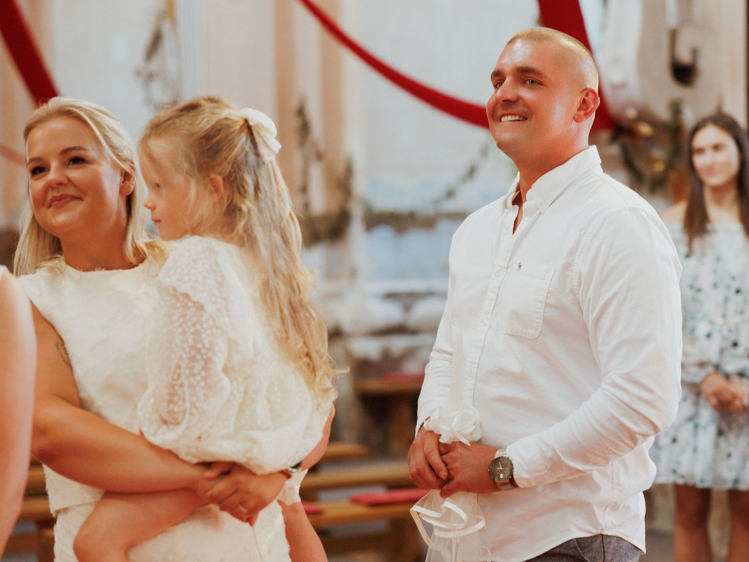 Wedding guests in white attire gather together for a candid celebration moment outdoors.