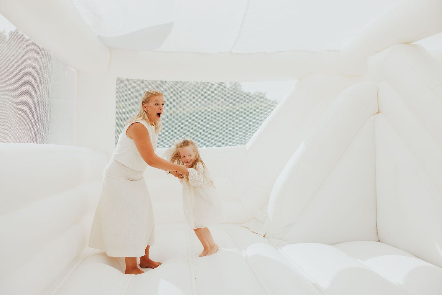 People having fun on white bouncy surface with lake view in background.