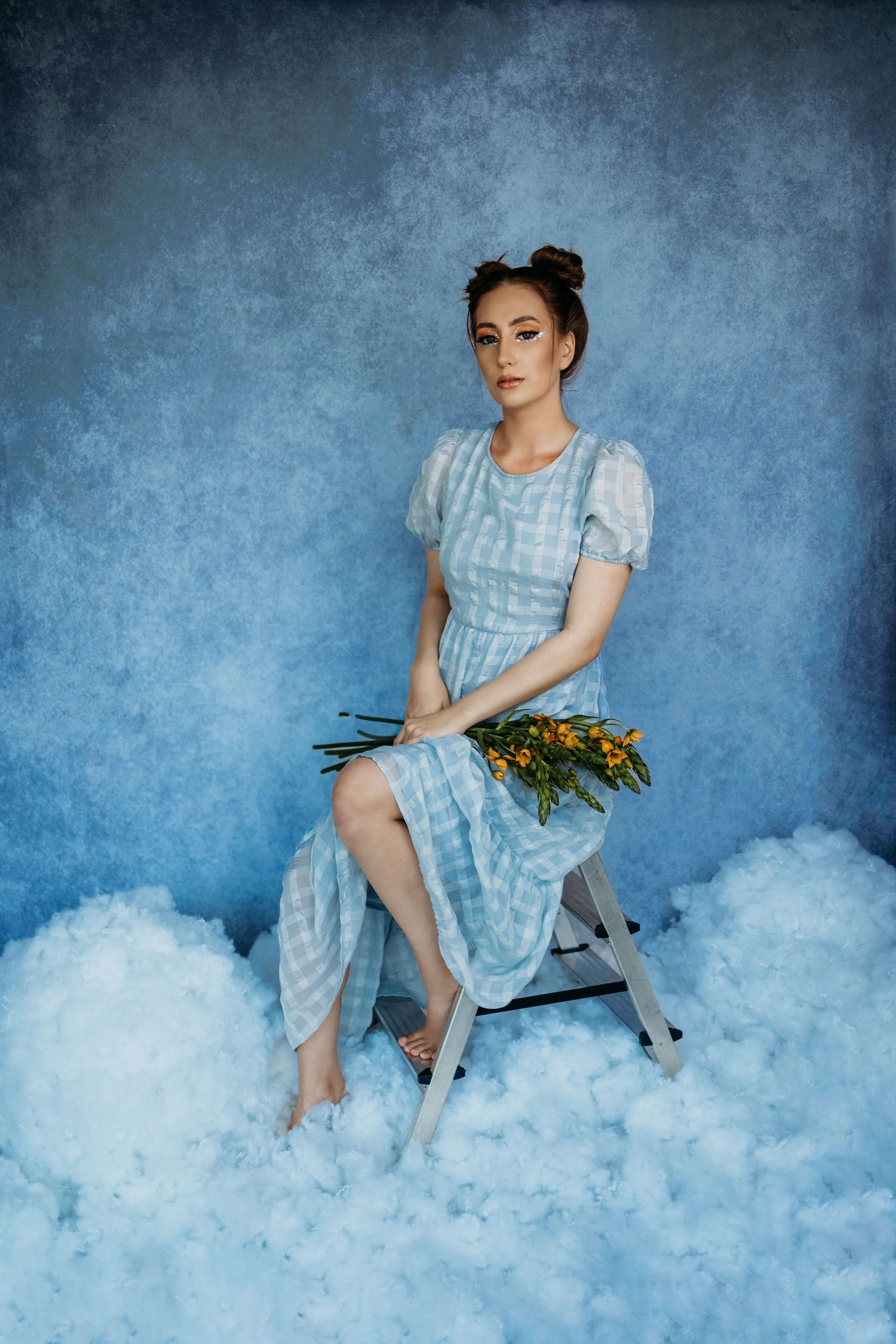 Fashion shoot with light blue dress against cloudy backdrop.