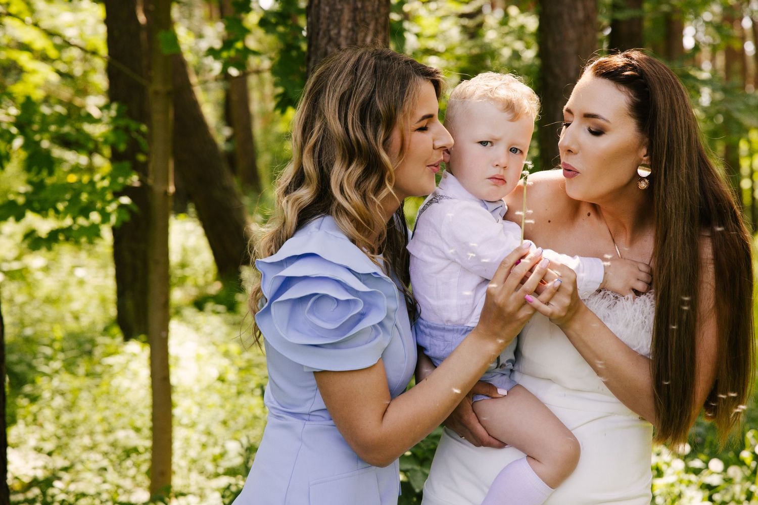 Sweet outdoor family photoshoot in a sunlit wooded area with soft natural lighting.