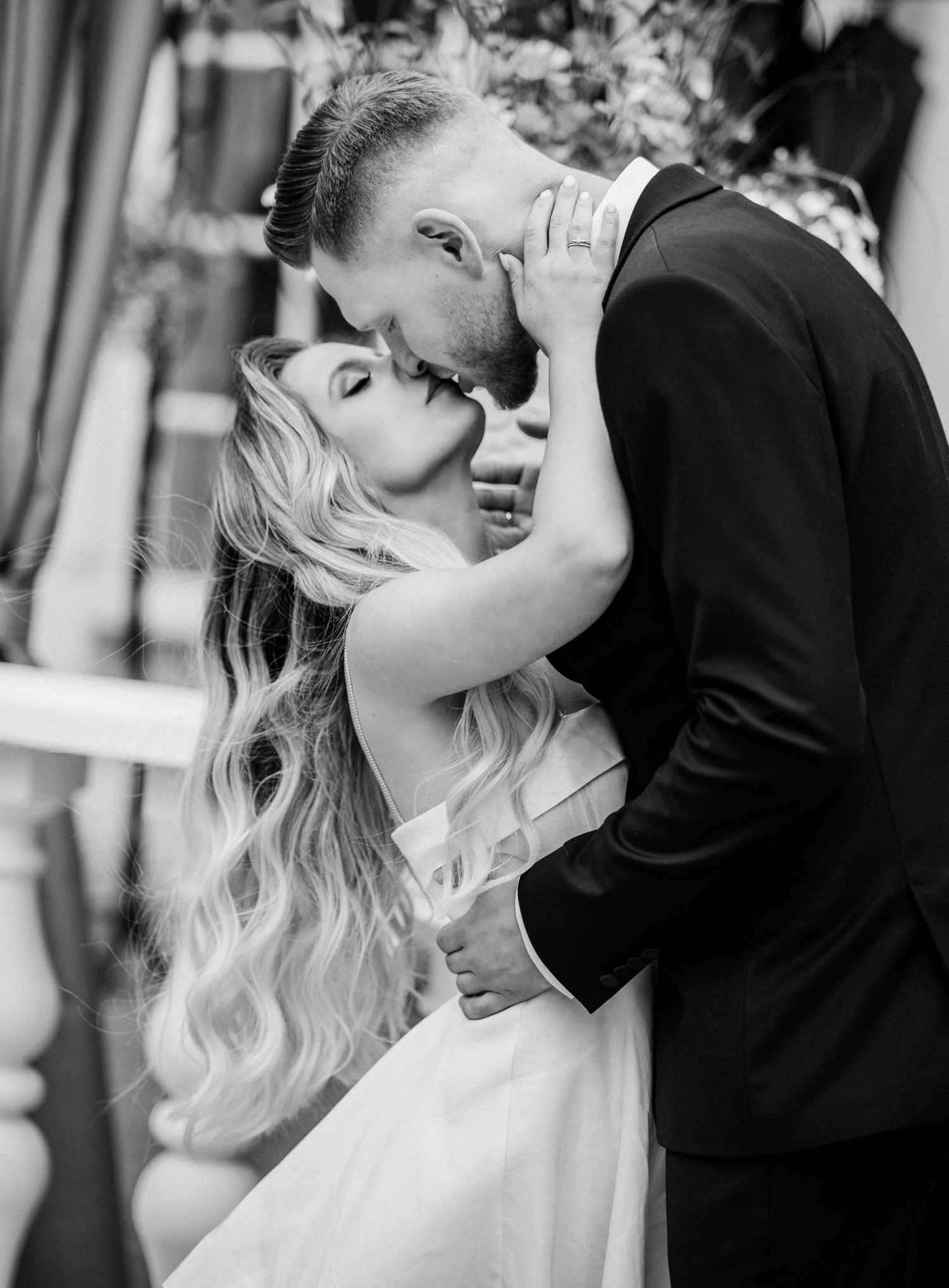 A romantic black and white wedding photo series showing a couple embracing and kissing during their celebration.