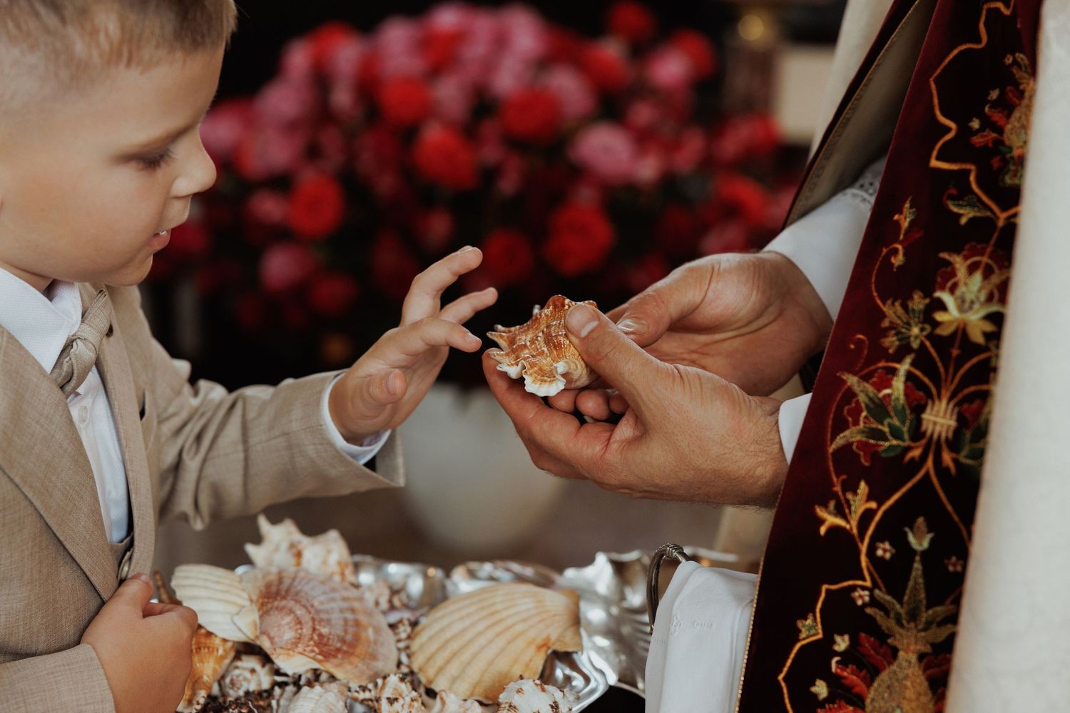 Wedding guests enjoy delicate desserts and champagne at an elegant reception with red floral decor.