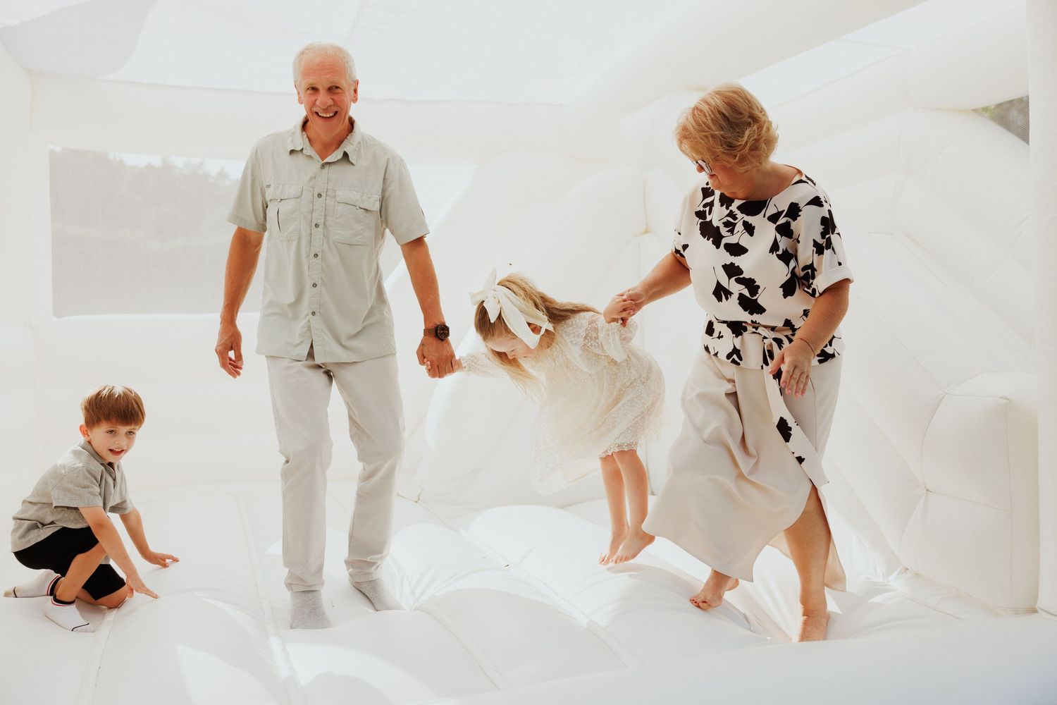 Family dressed in white creates candid moments during indoor photo session.