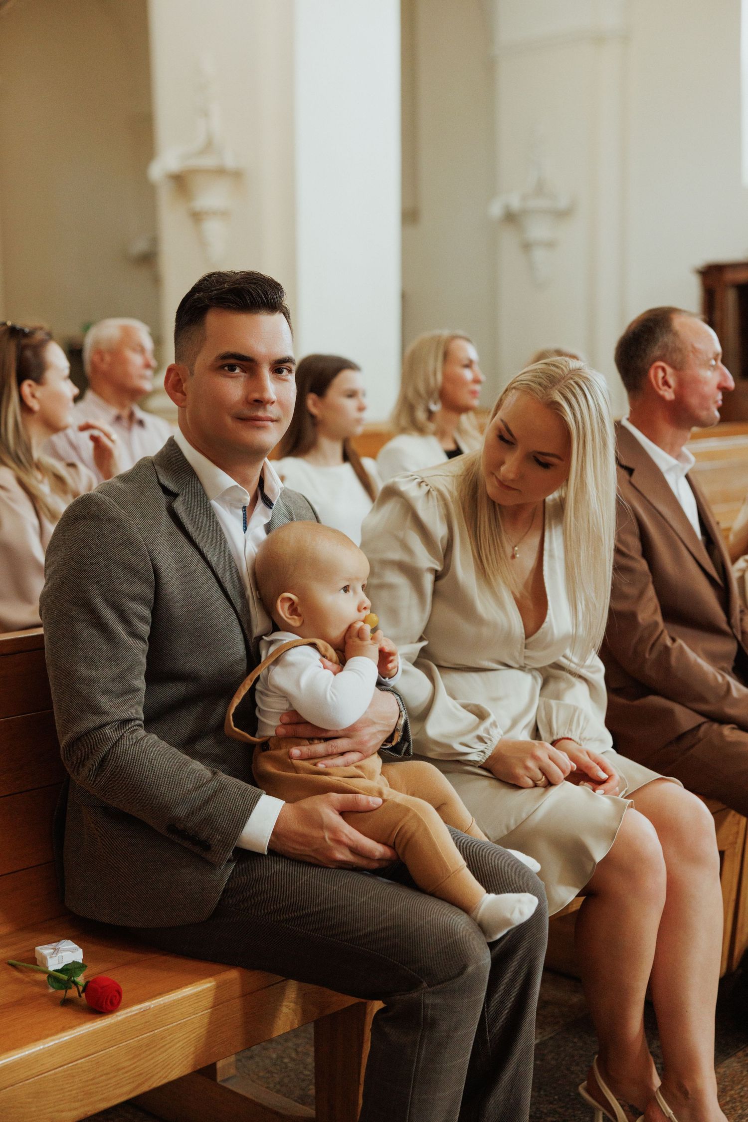 People seated in wooden church pews during a formal ceremony.
