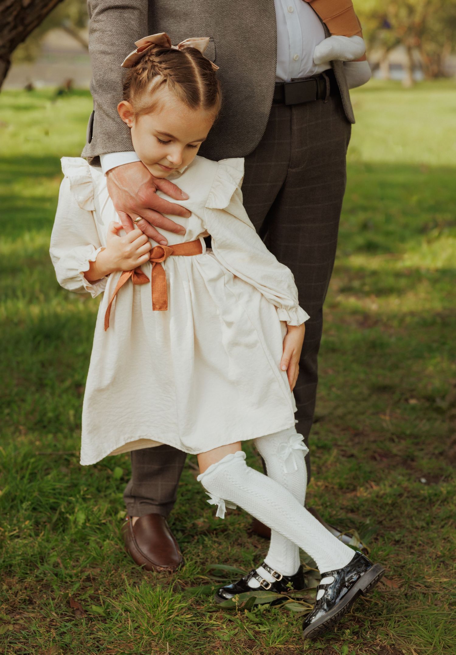 Close-up view of shoes and clothing details during an outdoor family photoshoot on grass.