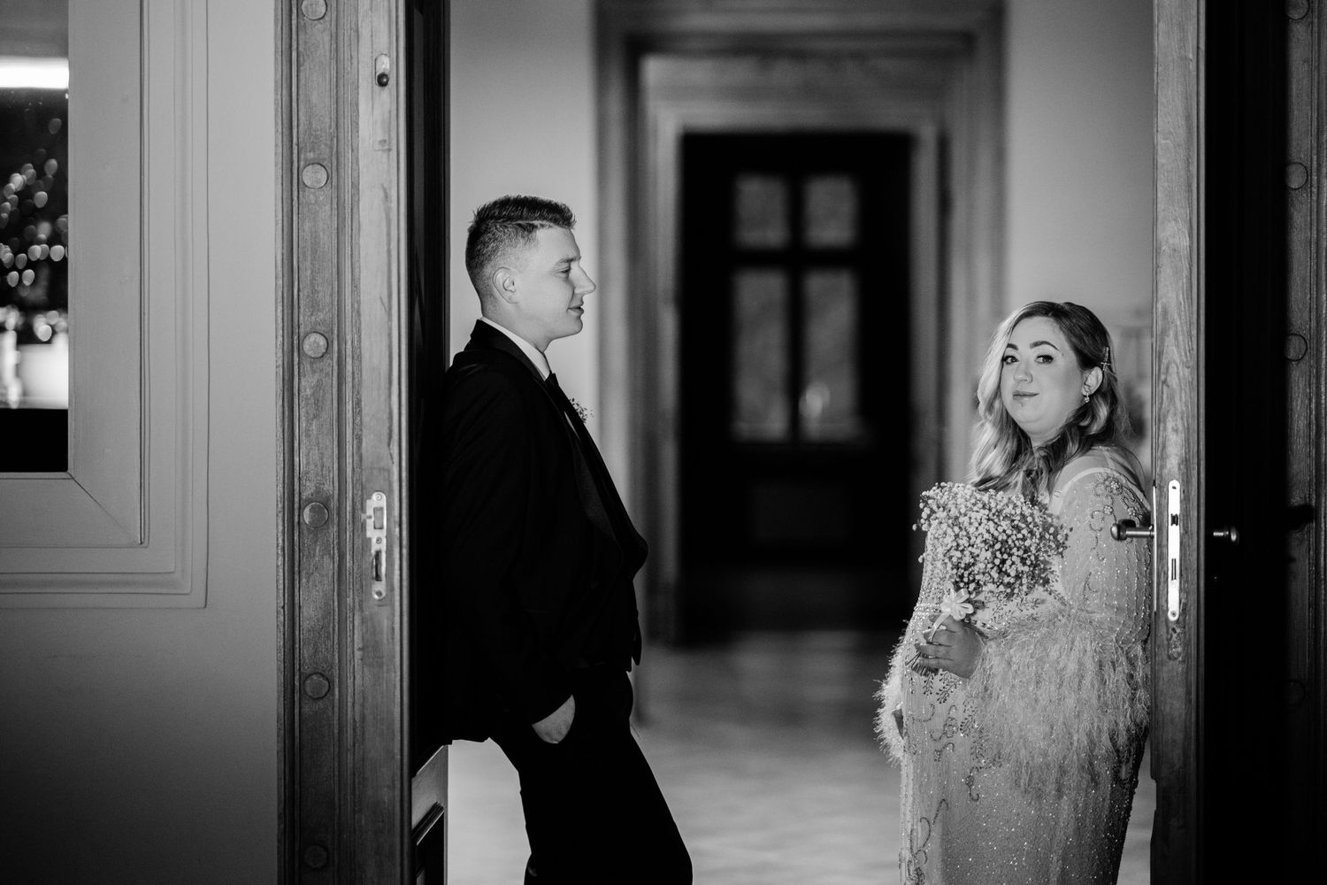 Artistic black and white wedding photography in elegant hallway with natural light.