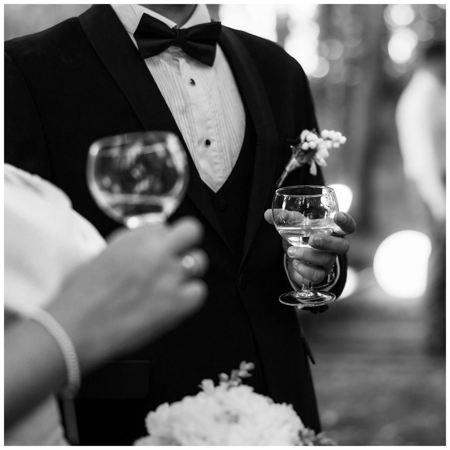 Close-up details of formal black tie attire and champagne glasses at an elegant event.