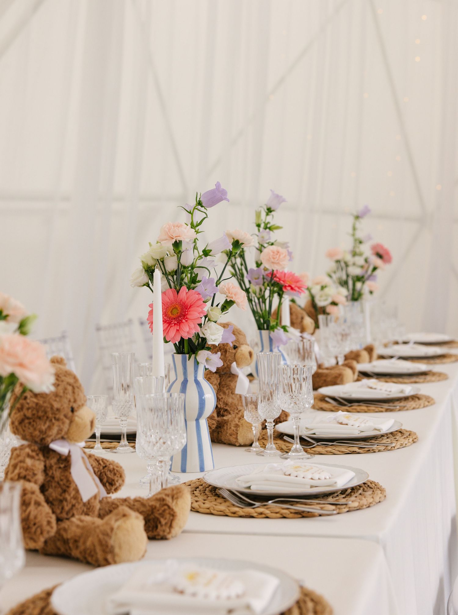Baby shower table settings with teddy bears, wicker placemats, and pink floral centerpieces.