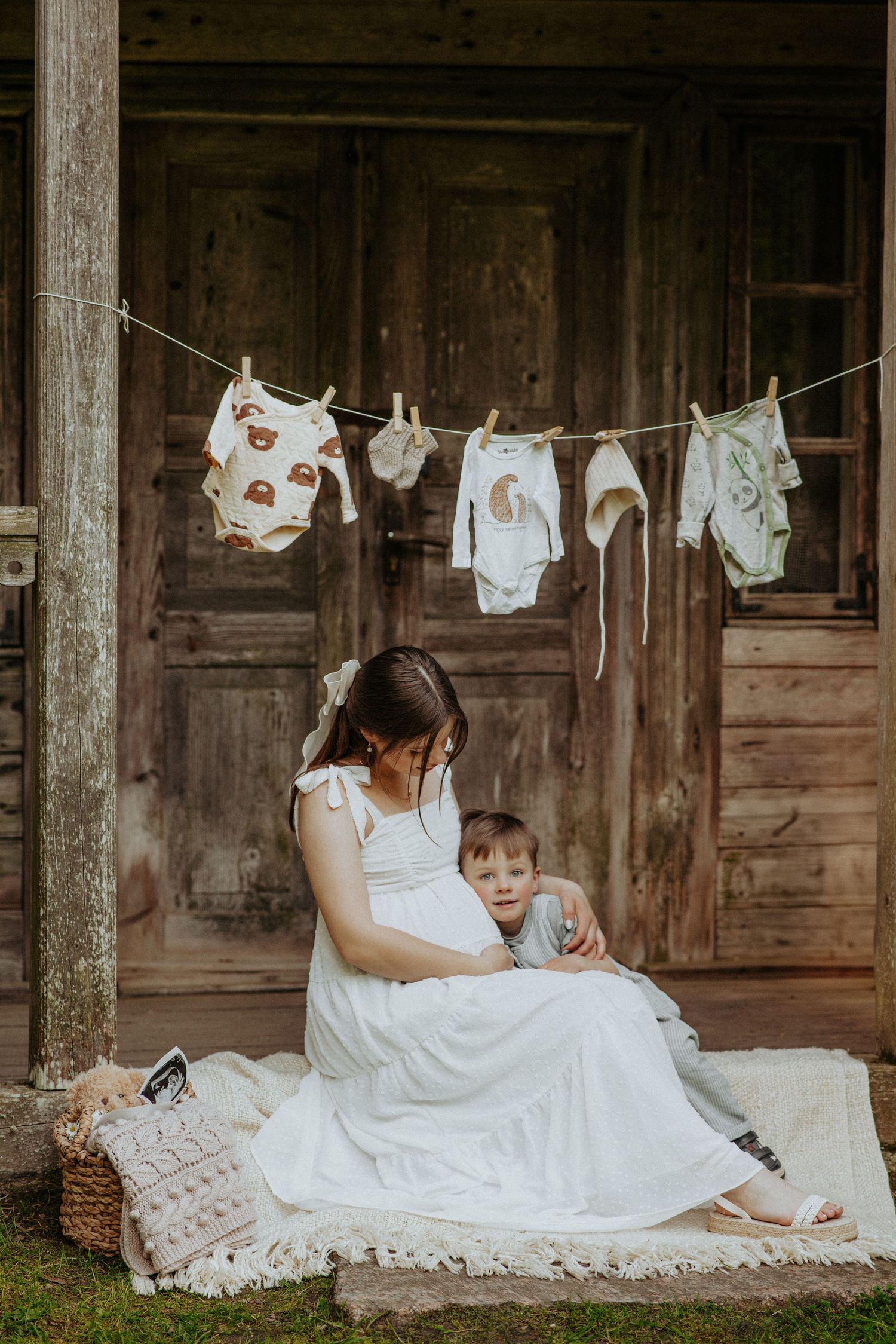 Mother and child relaxing by vintage wooden porch with baby clothes on clothesline.