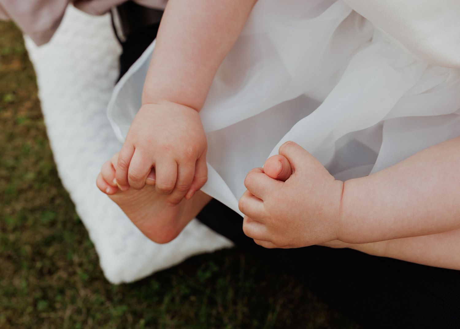 Close-up of tiny feet in white shoes and frilly socks against tulle dresses.