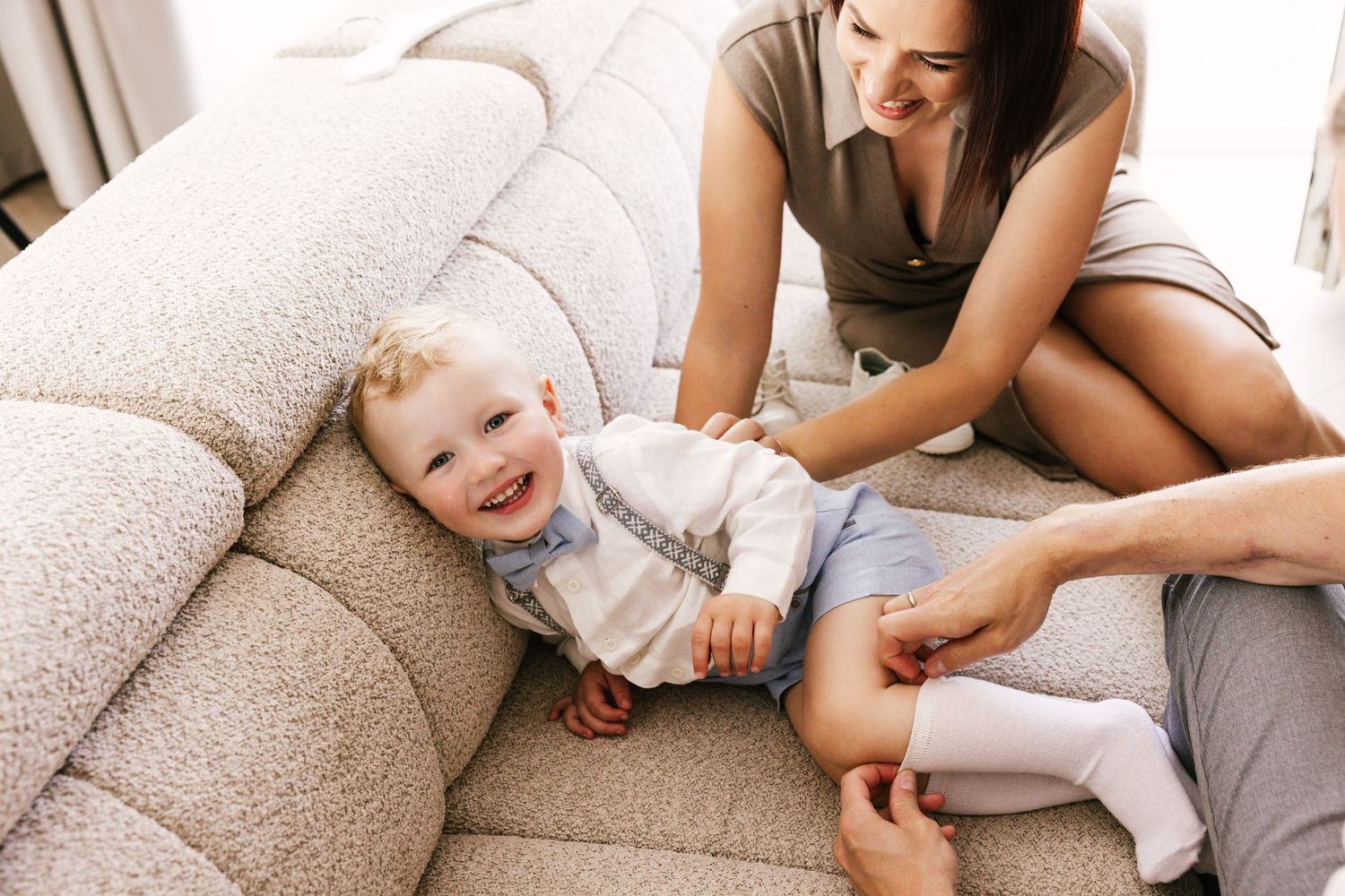 Family sharing tender moments together on a comfortable grey couch in a bright living room.