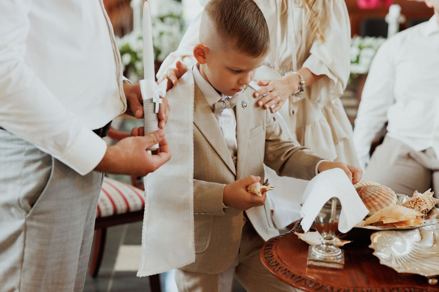 People in white and beige attire gathered around a table during a meal service at an event.
