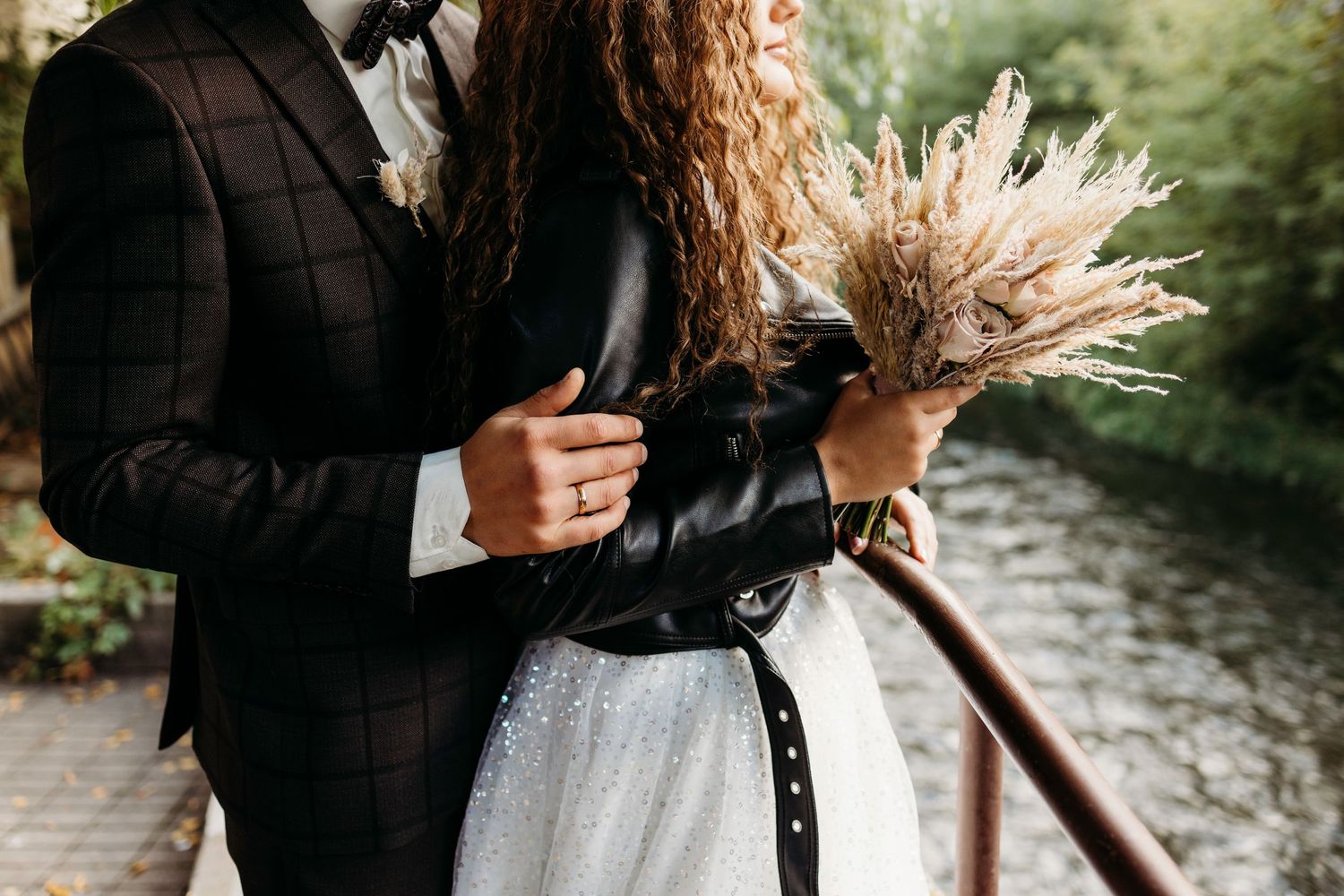 Romantic couple embracing outdoors with sunlit curly hair and formal attire.