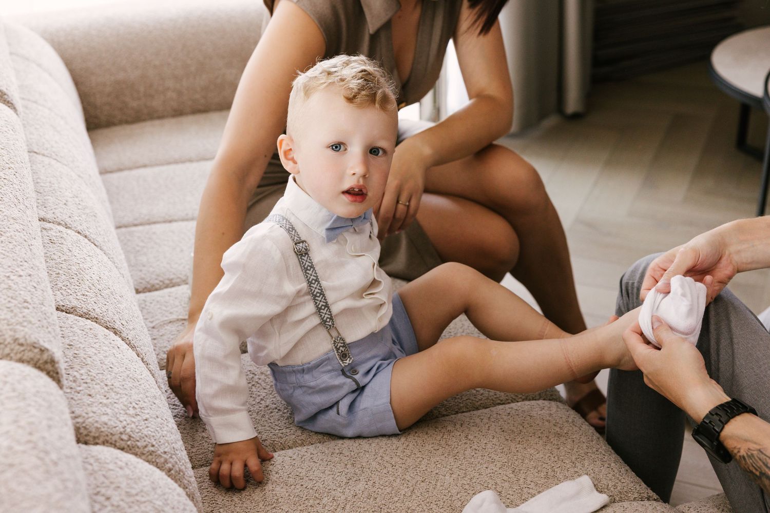 Toddler in formal outfit sitting on couch during dress-up session.