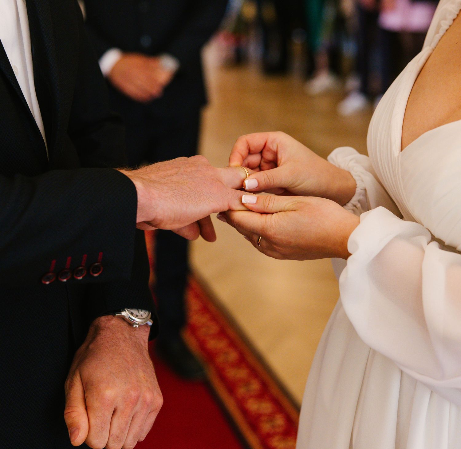 A close-up of hands exchanging wedding rings during a ceremony.