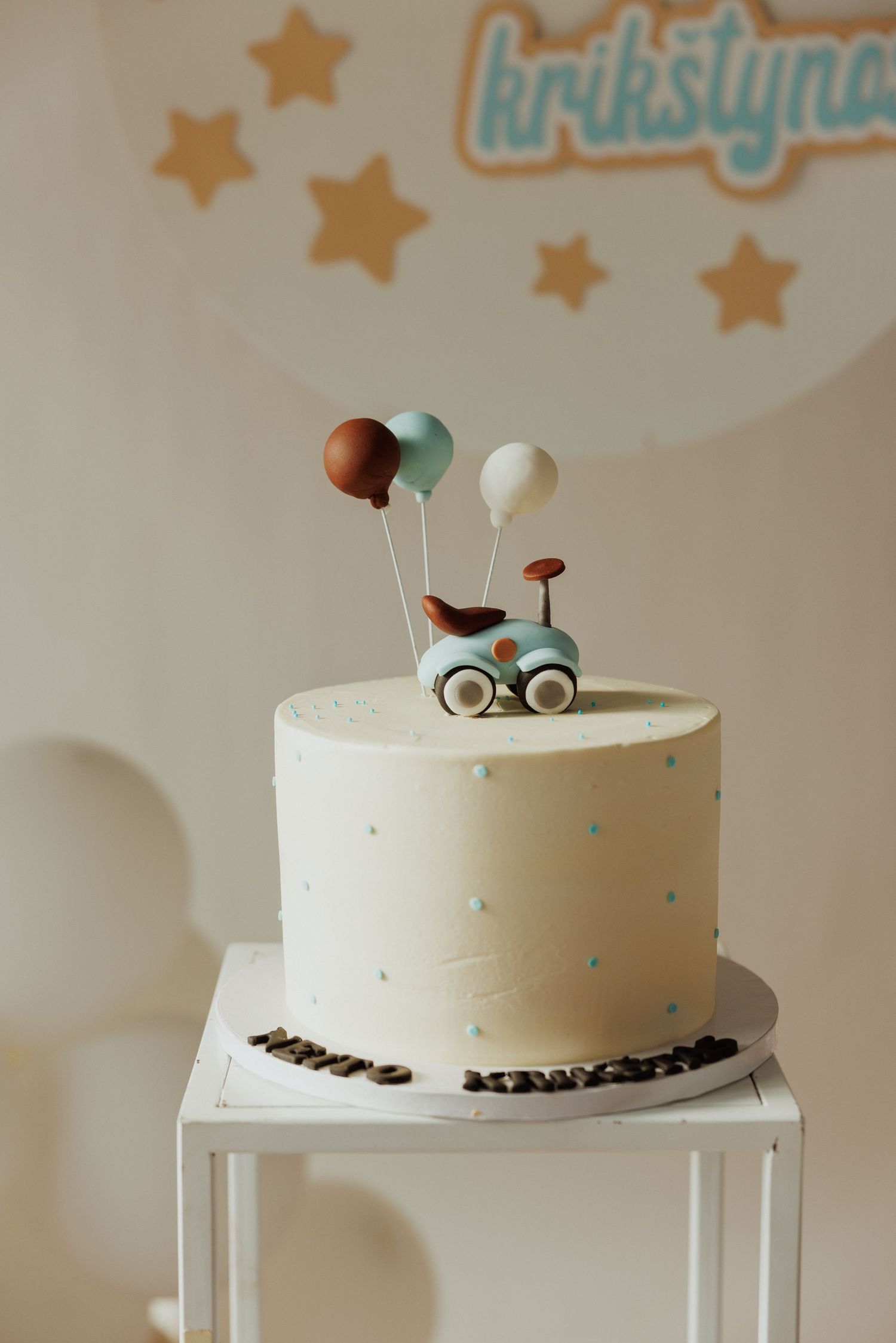 White frosted cake with minimalist decorations on a white pedestal stand against a starry backdrop.