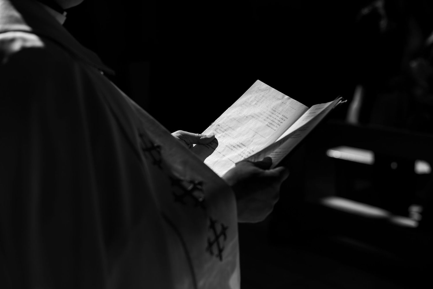 A person in a dark uniform holds sheet music during a performance, captured in black and white.