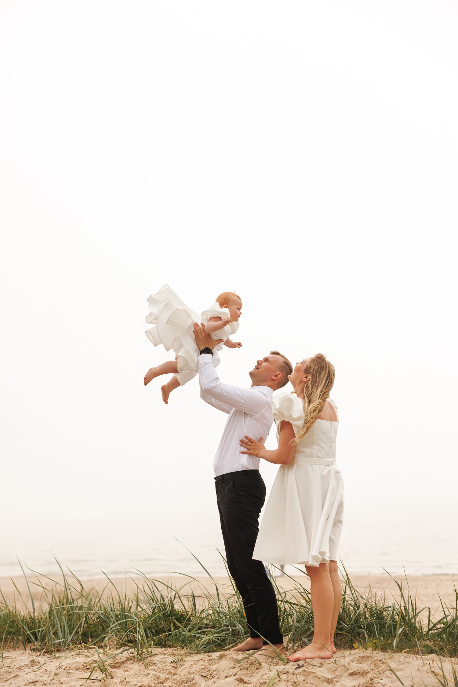 A couple shares a romantic moment in a series of silhouetted poses against a light background with grass below.