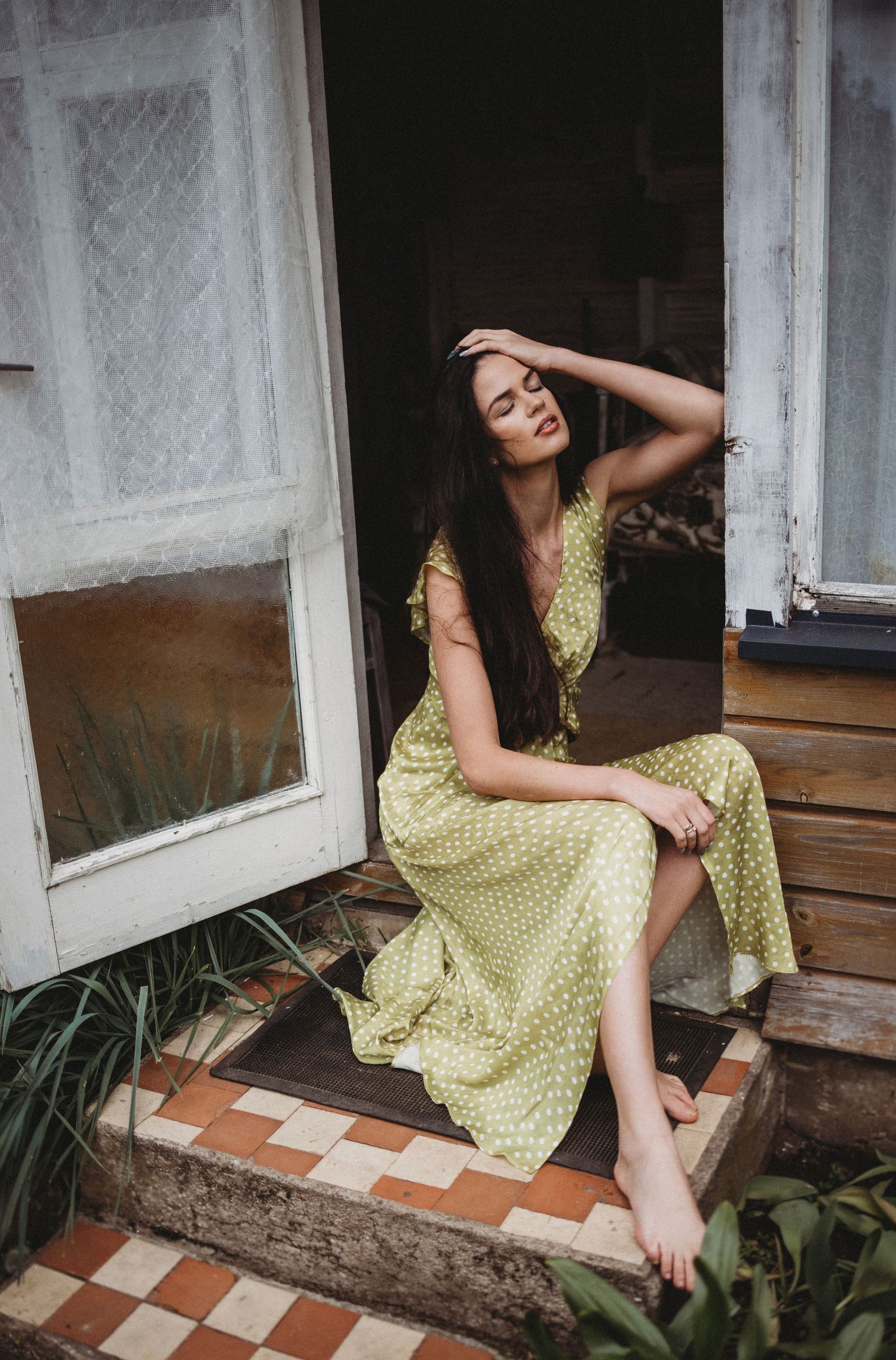 Vintage-style portrait on wooden porch steps with yellow polka dot dress.