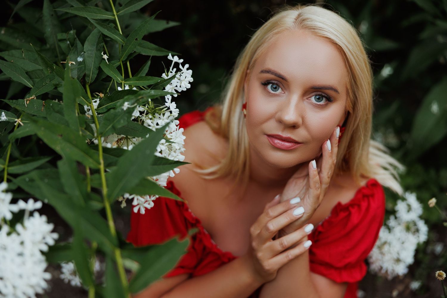Portrait among white flowering bushes with woman in red dress.
