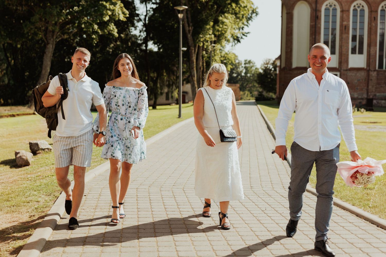 Group walking together on stone pathway near historic brick building.