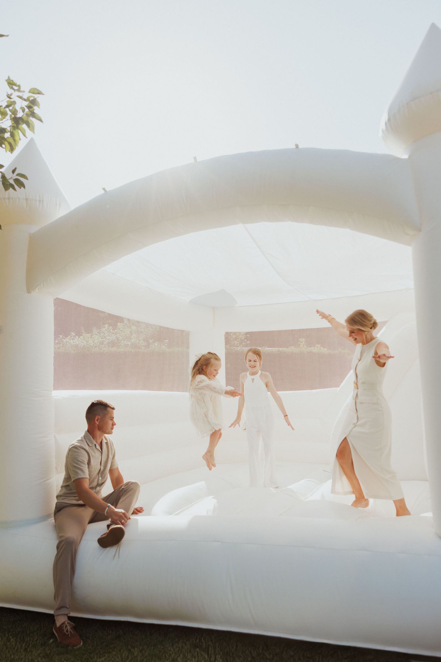People jumping and playing on a large white bounce house or inflatable structure outdoors.