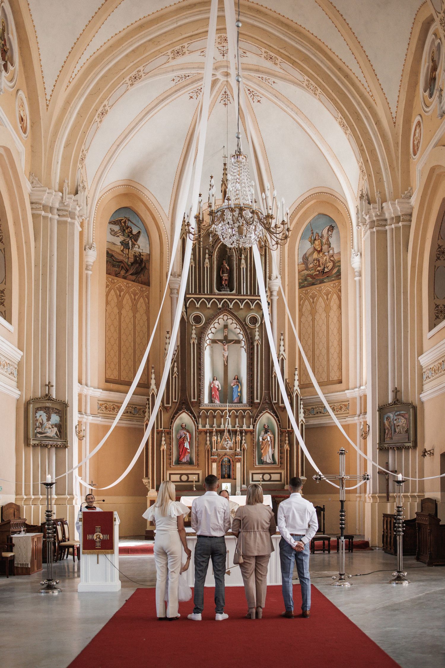 Interior of an ornate Gothic church with vaulted ceilings, arches and decorative white ribbons.
