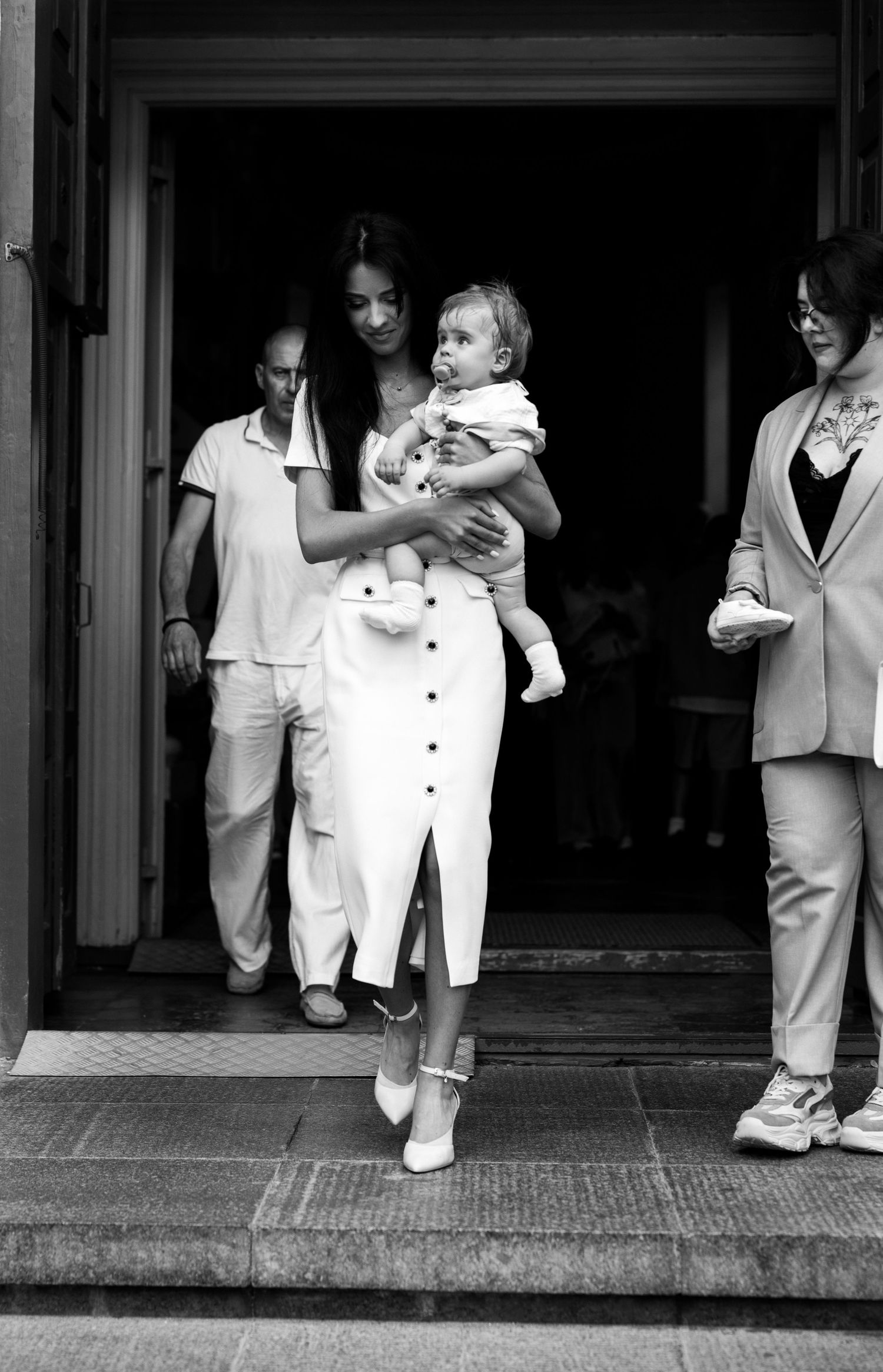 A black and white photograph showing a group of people in white clothing standing in a doorway.