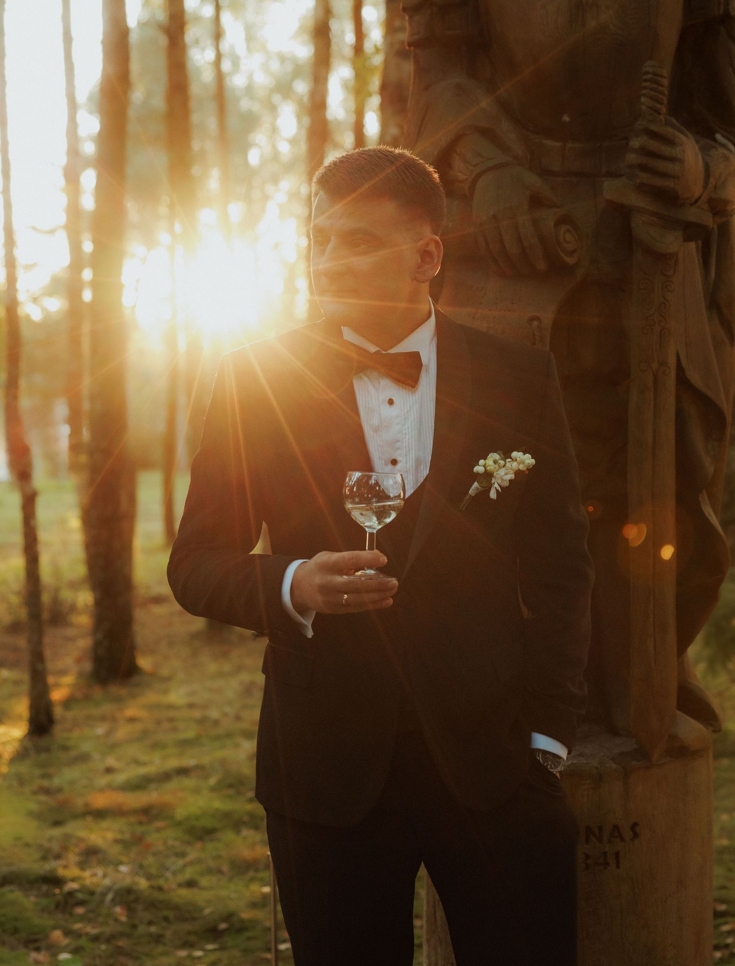 Golden sunlight streams through trees as formal attire is captured in silhouette.