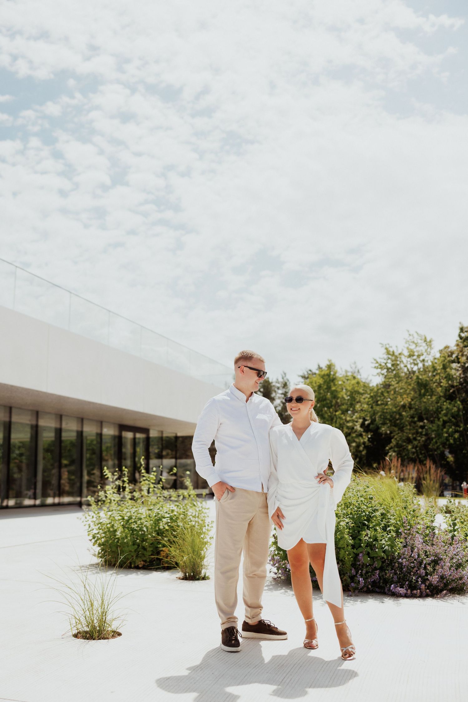 People in white clothing walking and playing on a modern concrete patio with landscaping.