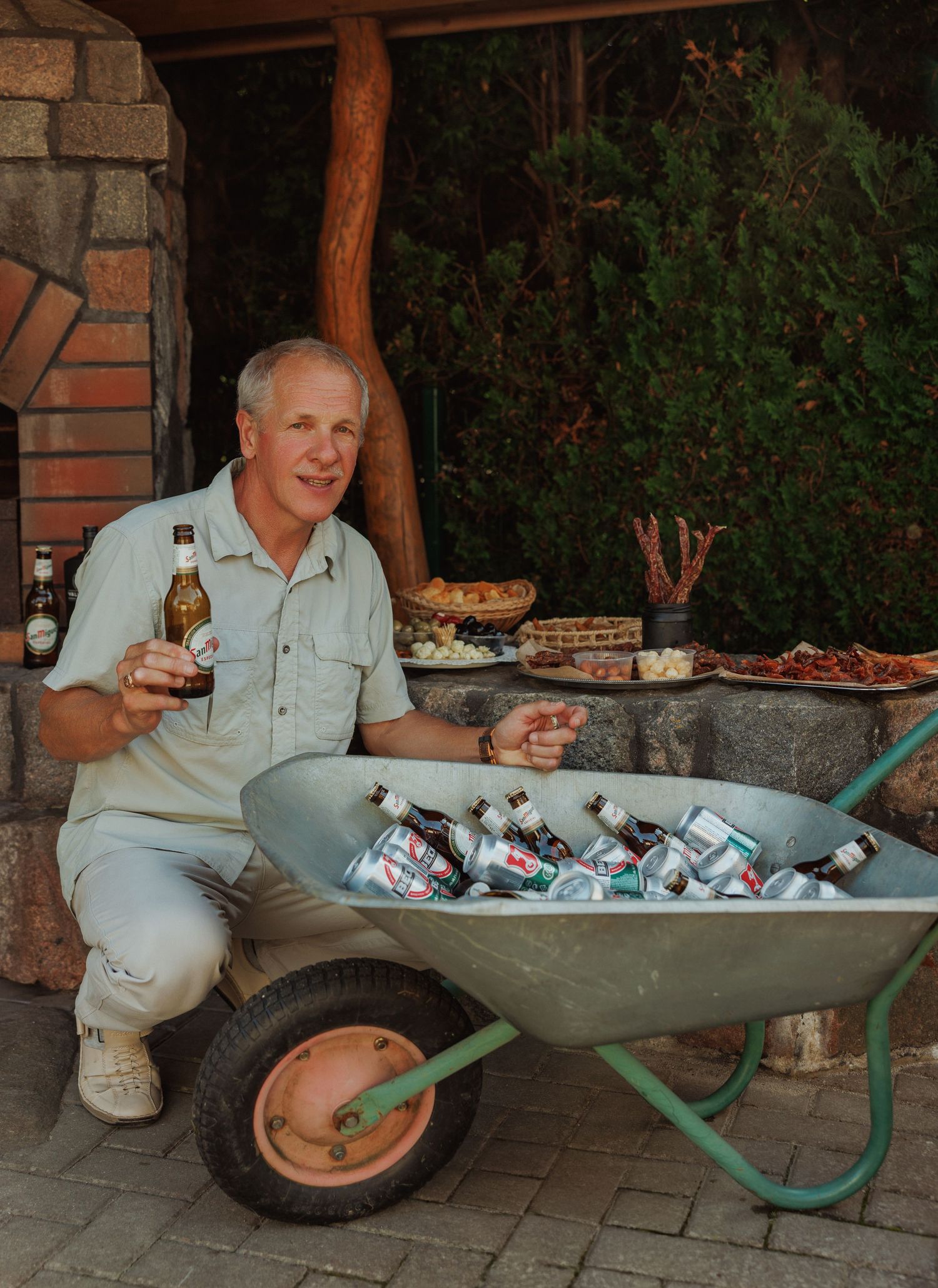 A wheelbarrow filled with drinks and ice serves as a rustic beverage cooler at an outdoor event.