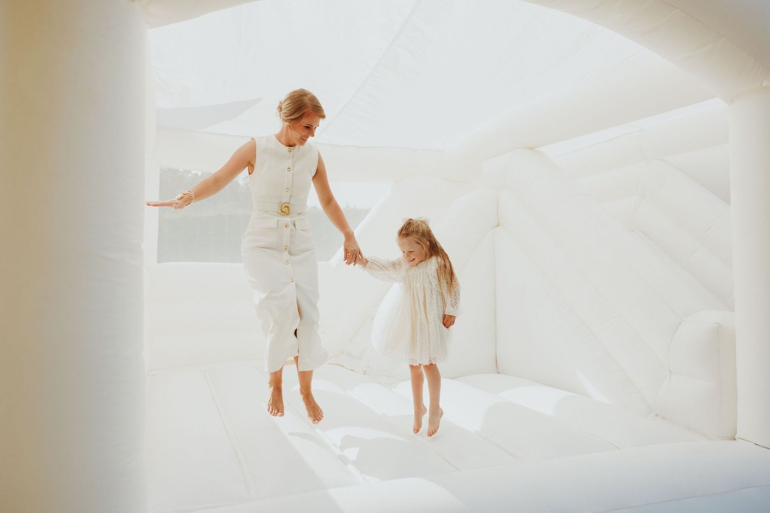 Children in white outfits play and dance together in bright indoor setting.