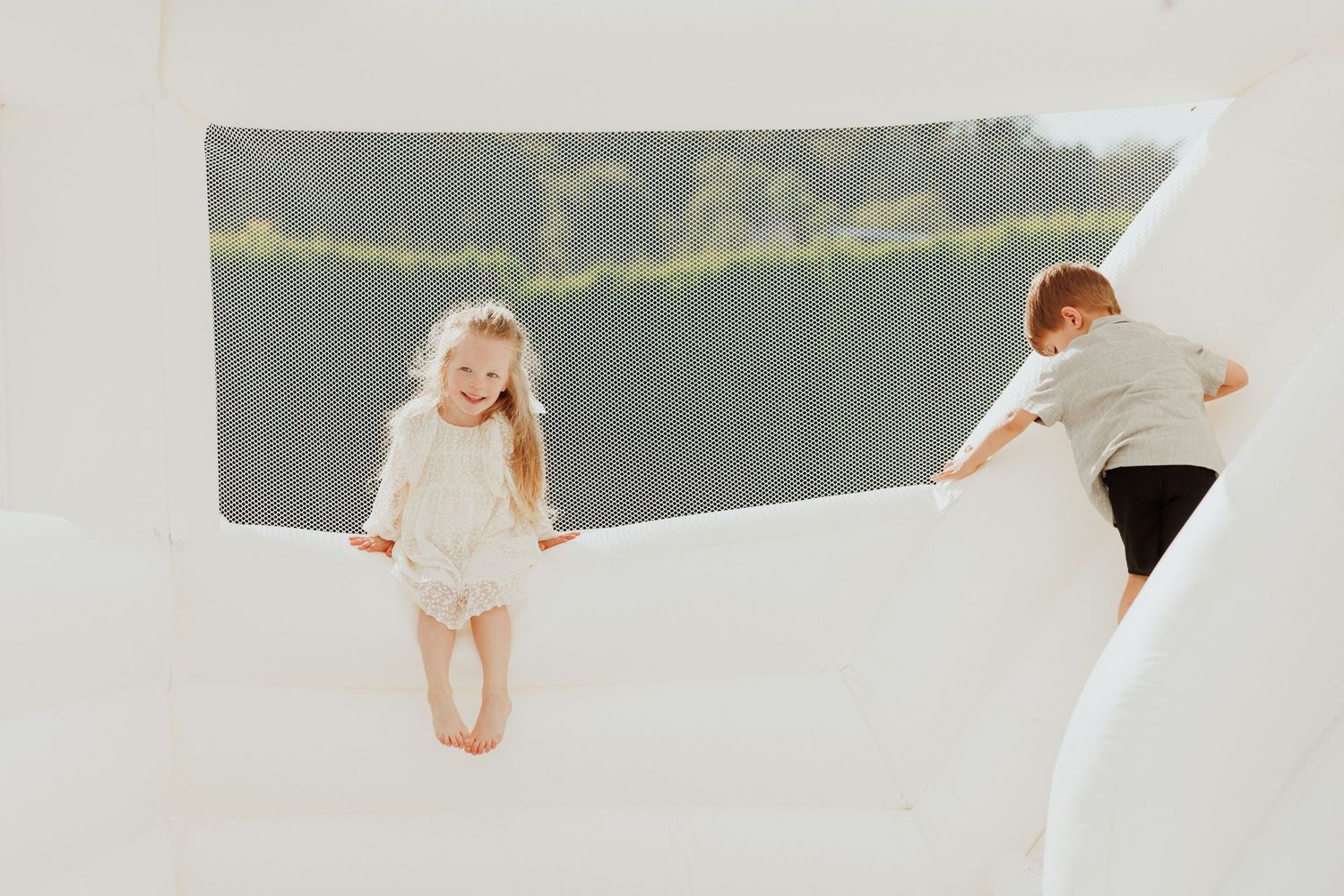 Two people playing on white inflatable surface with scenic backdrop.